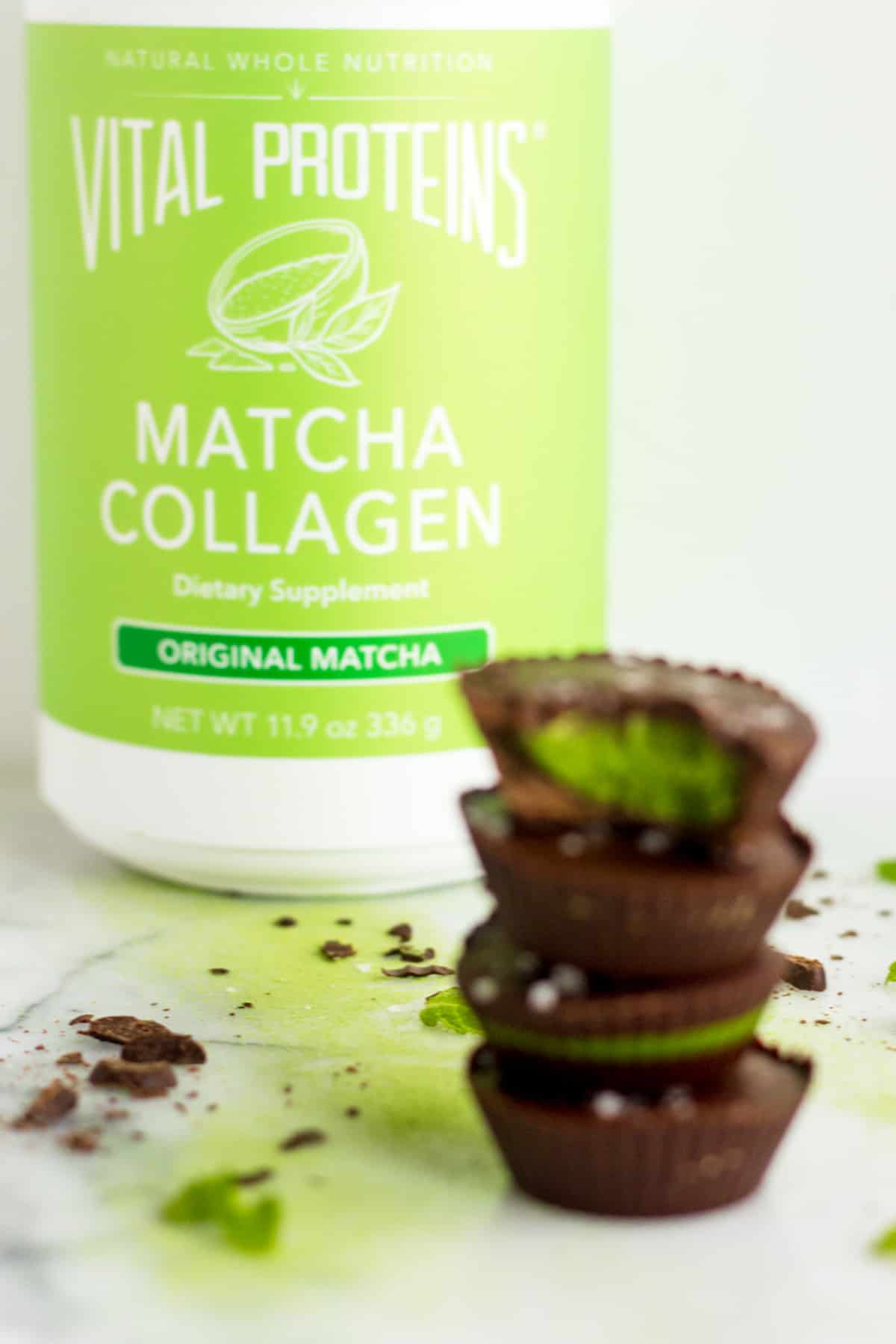 4 Collagen Mint Matcha Coconut Butter Cups stacked on drop of each other with a container of Vital Proteins Matcha Collagen in the background in focus