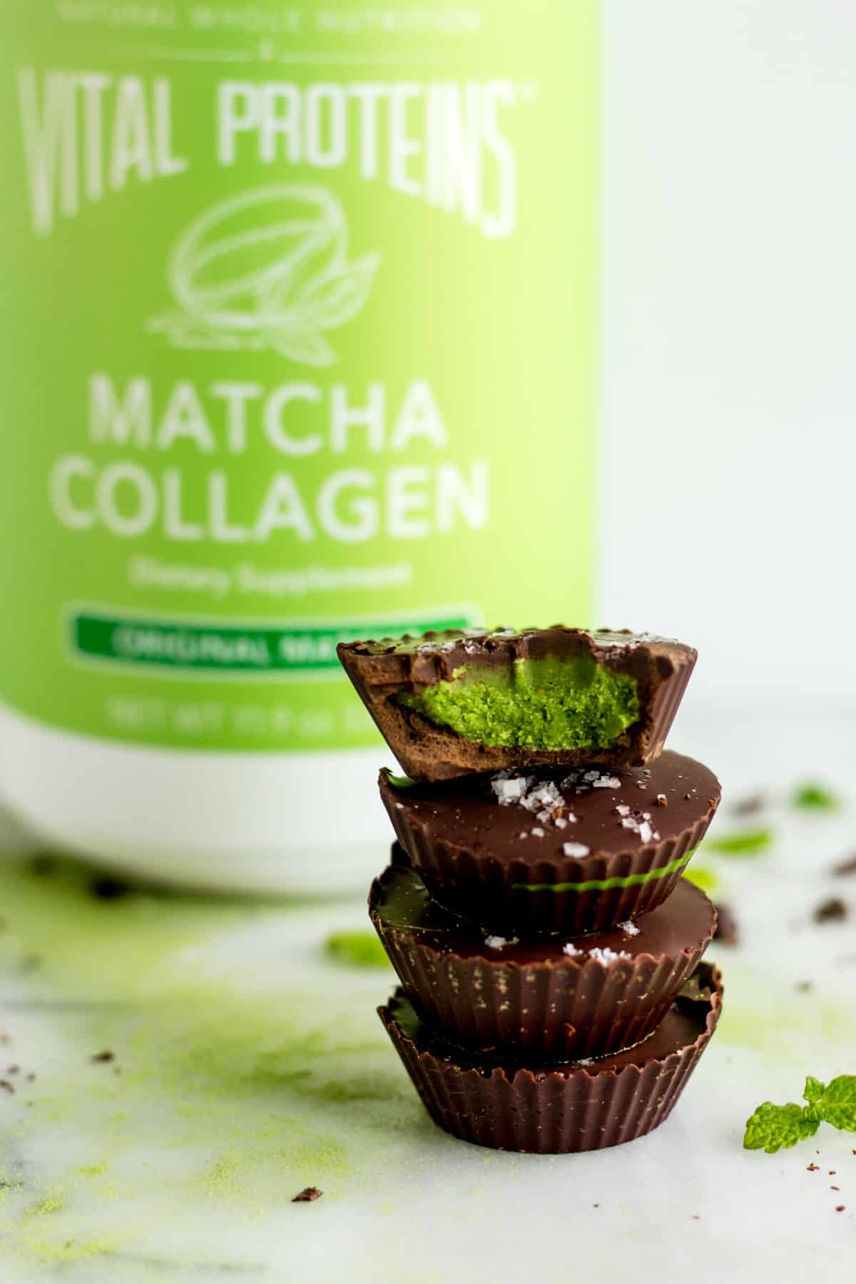 A stack of 4 Collagen Mint Matcha Coconut Butter Cups with a container of Vital Proteins Matcha Collagen in the background