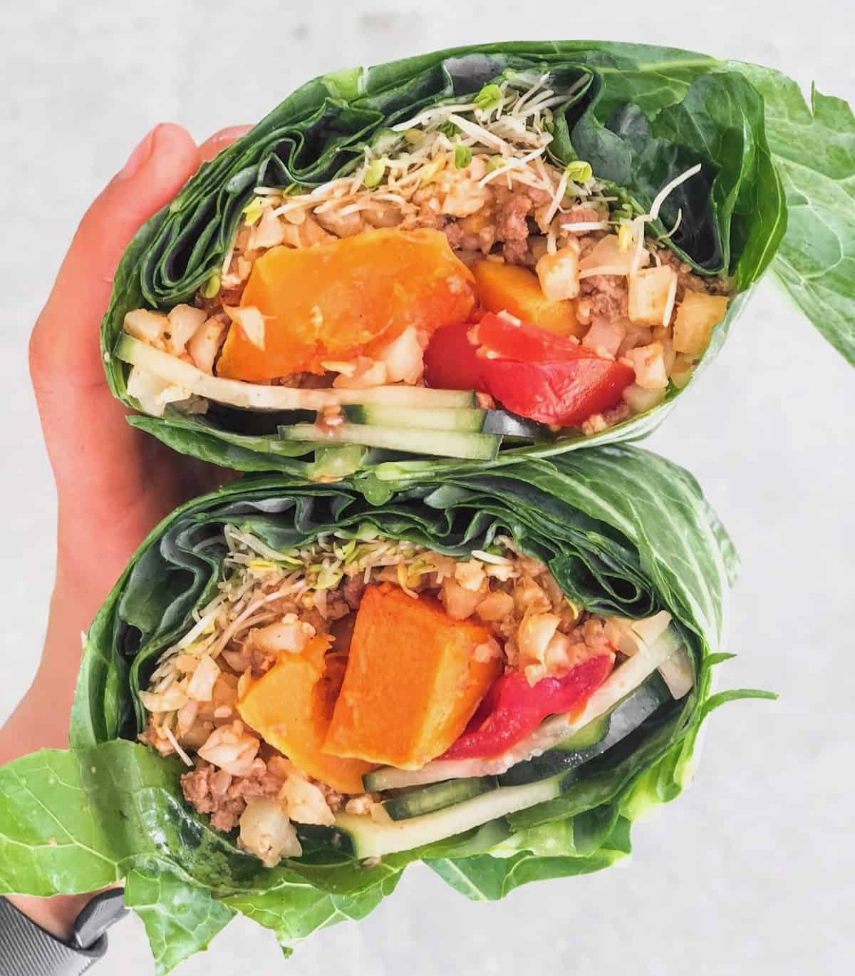 Collard wrap filled with ground beef, cauliflower rice, butternut squash, tomatoes, cucumber, and sprouts