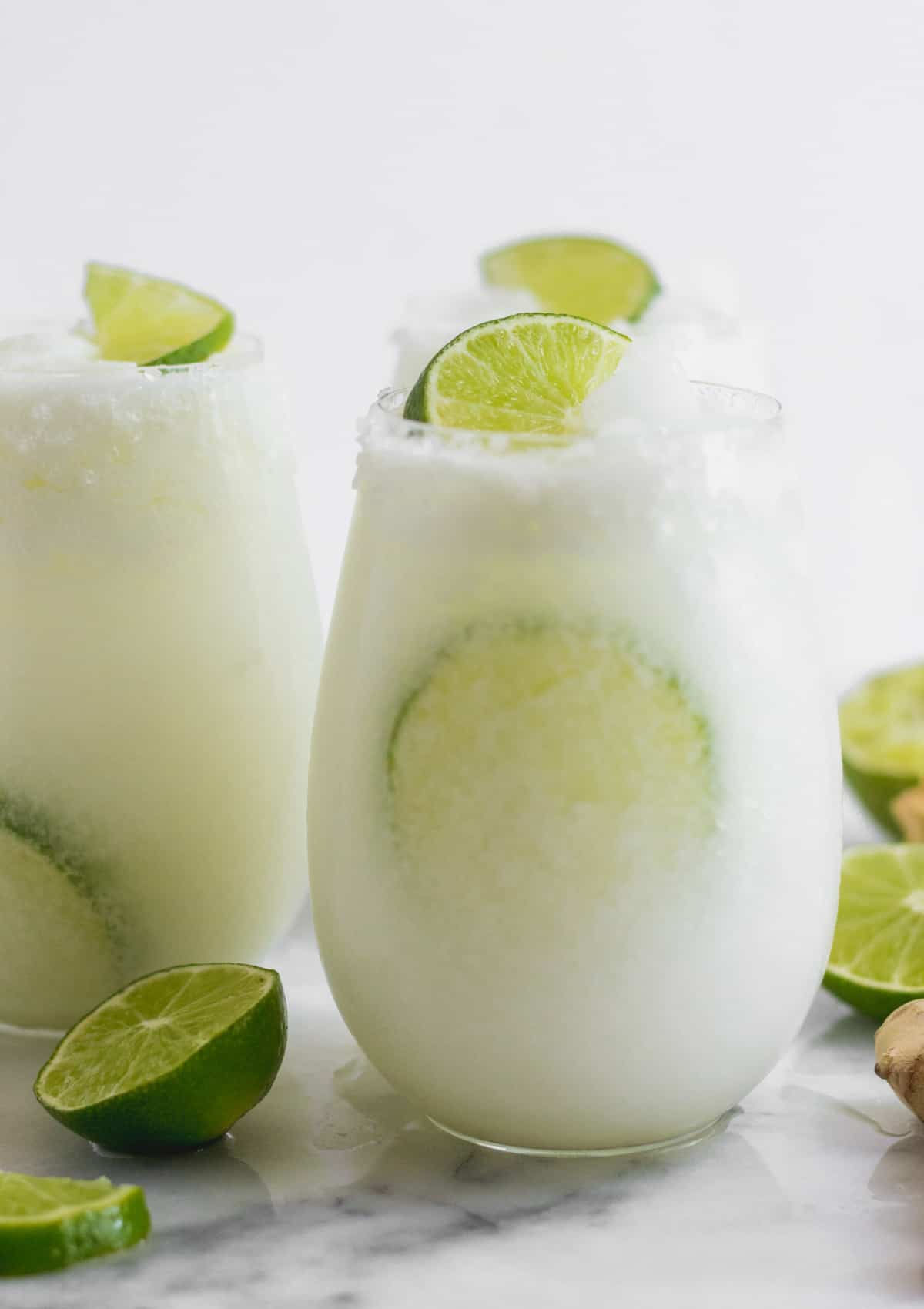 Glass filled with coconut lime mocktail with a lime in the glass and garnished with a lime wedge