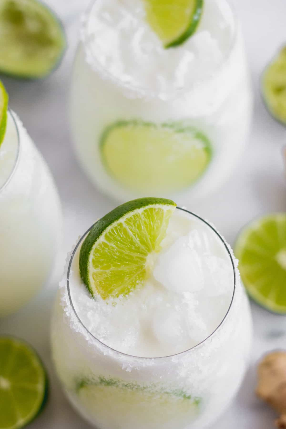 Overhead shot of 2 glasses filled with a coconut mocktail garnished with limes