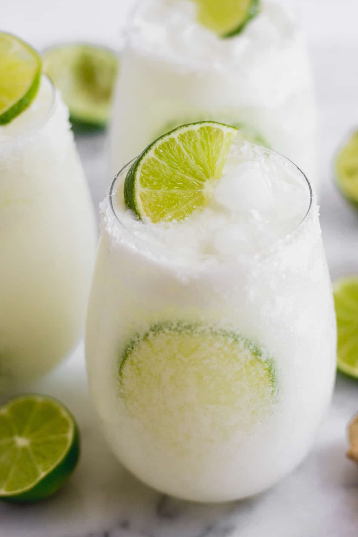 Glass with a salted rim filled with a coconut mocktail and limes