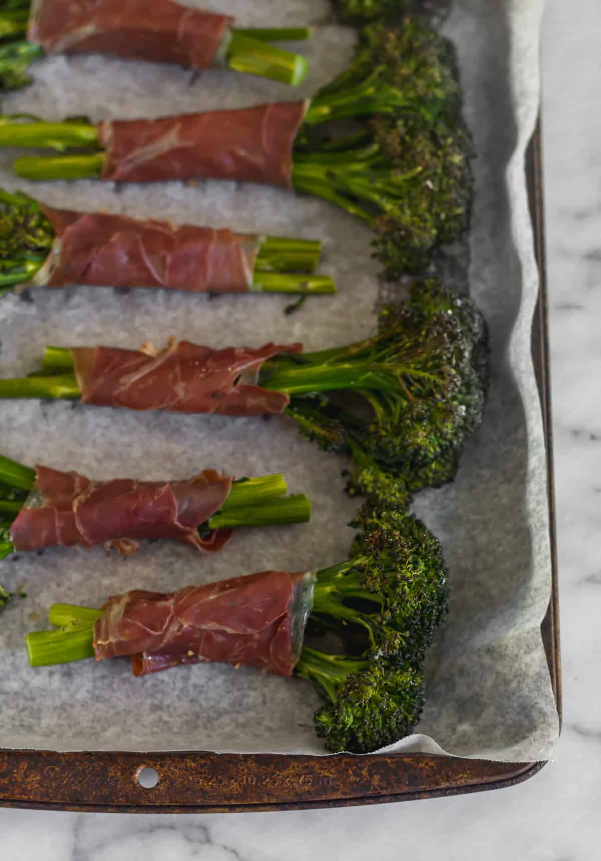 Pan of baked broccolini wrapped in crispy prosciutto after it was roasted in the oven