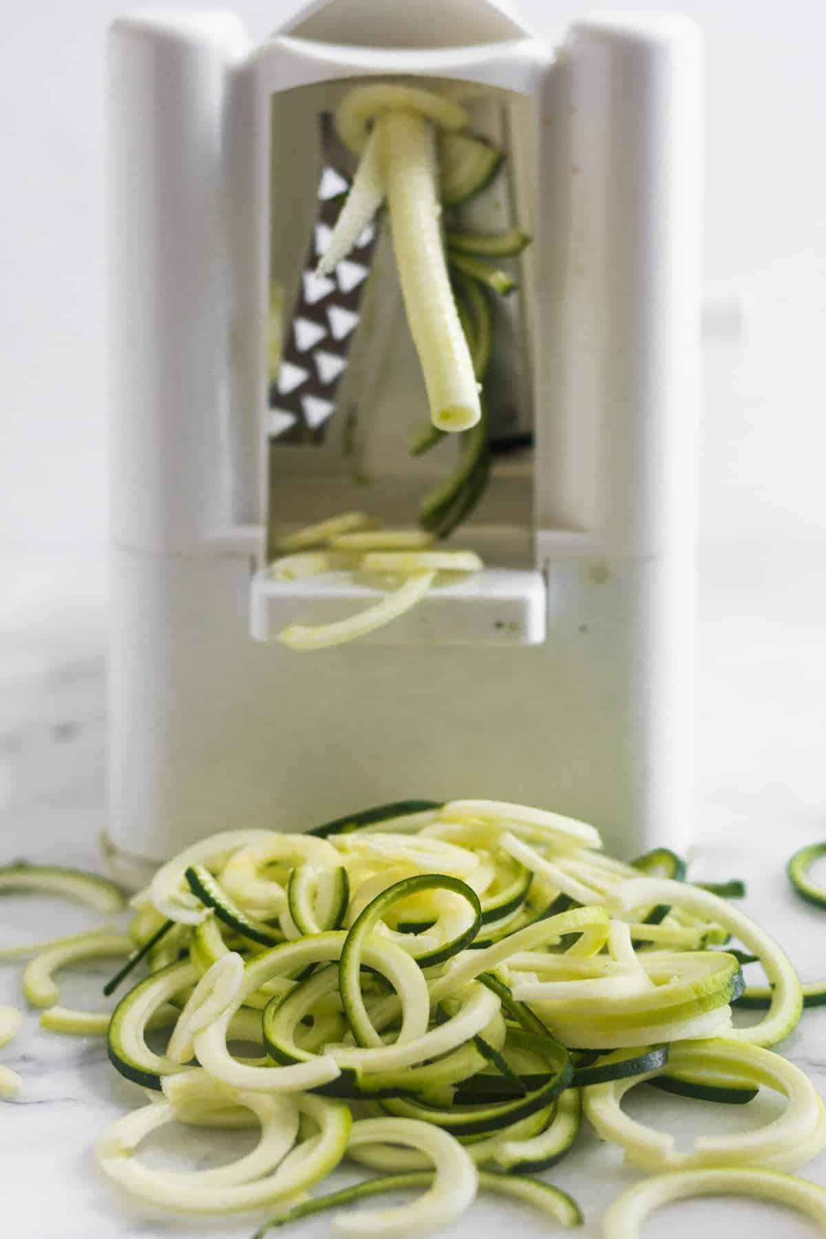 Spiralizer with zucchini noodles coming out of it