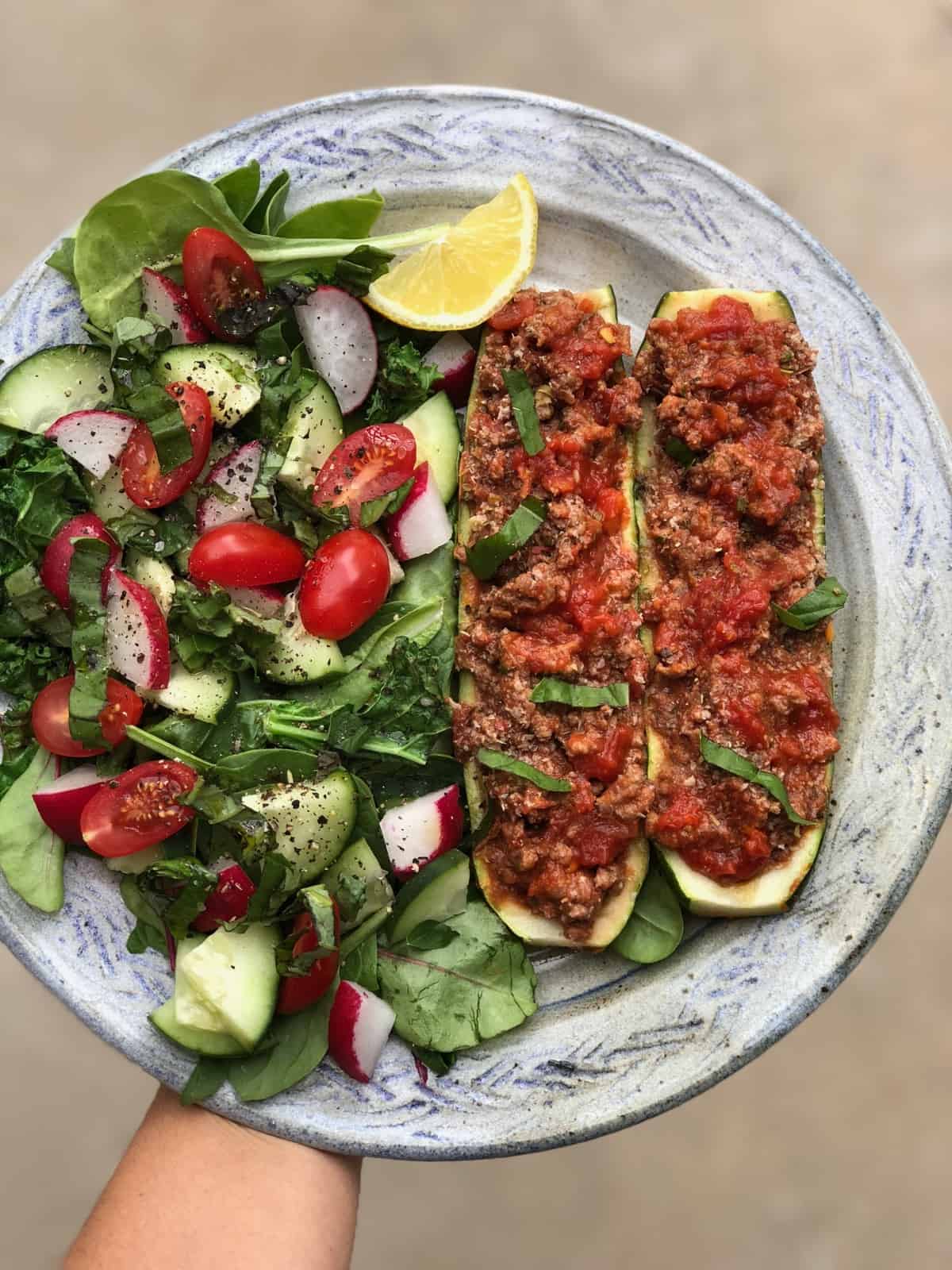 Plate with 2 beef stuffed zucchinis and a salad