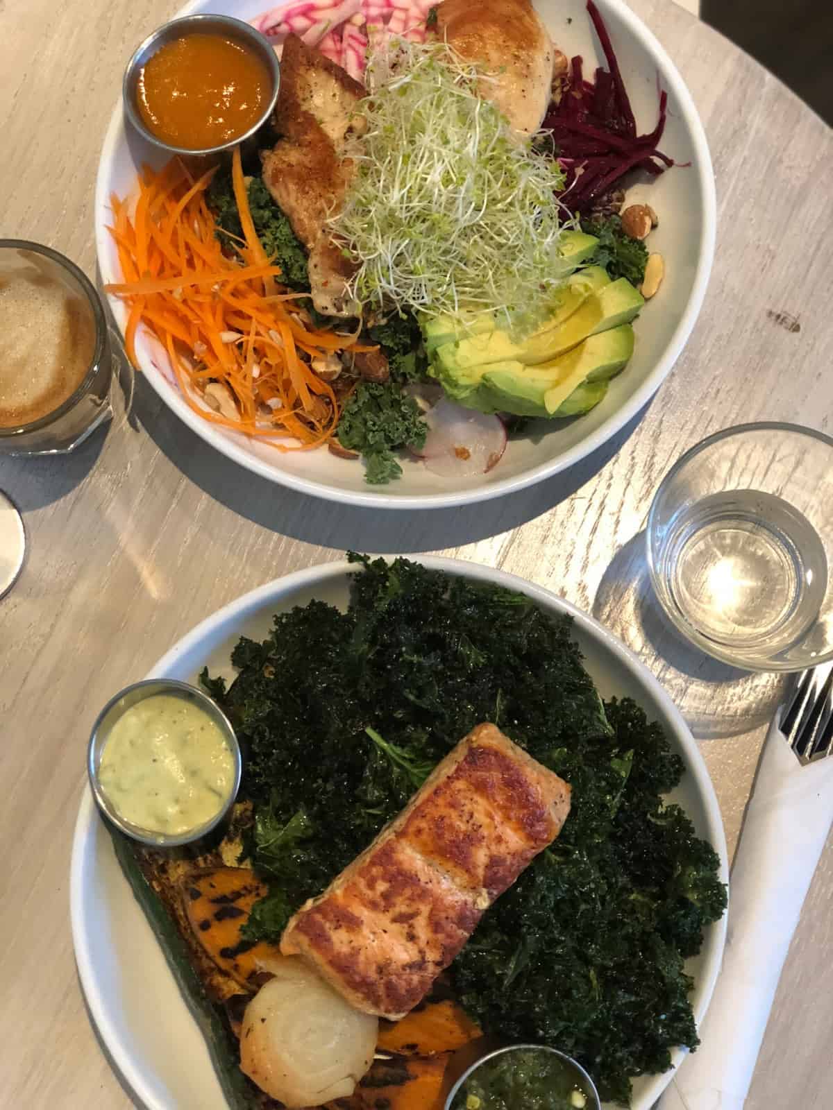 Two large bowls filled with veggies, greens, and protein