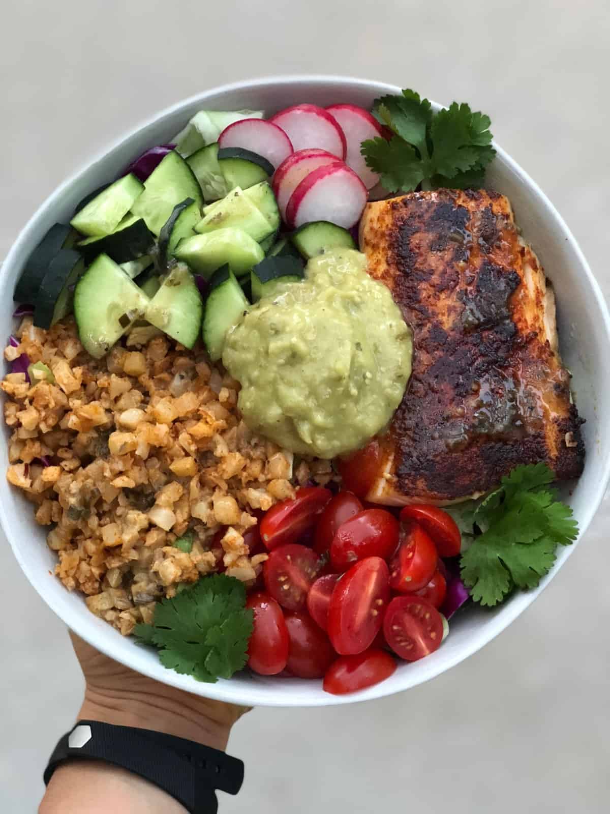 Big bowl of greens, chopped veggies, blackened fish, cauliflower rice, and tomatillo salsa