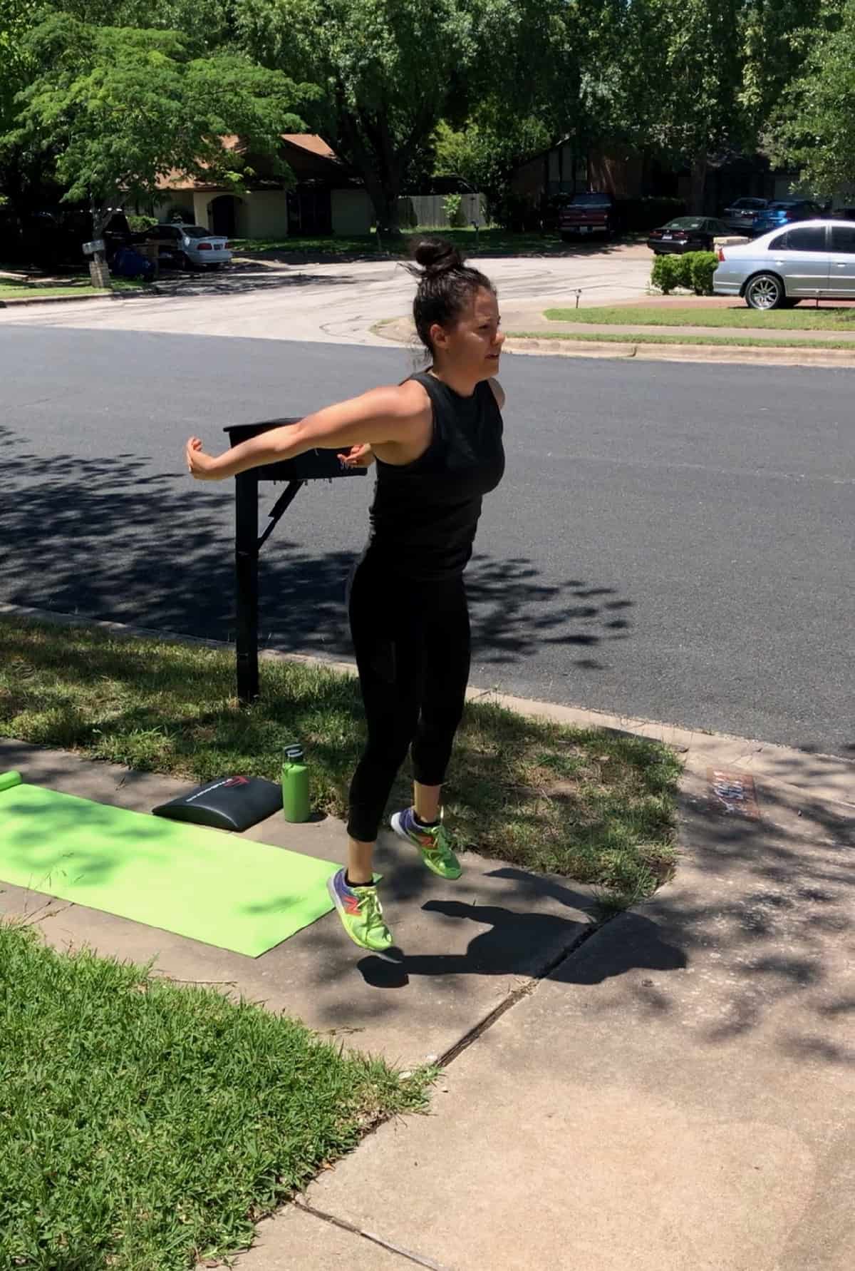 Girl doing a home workout outside doing jumping squats