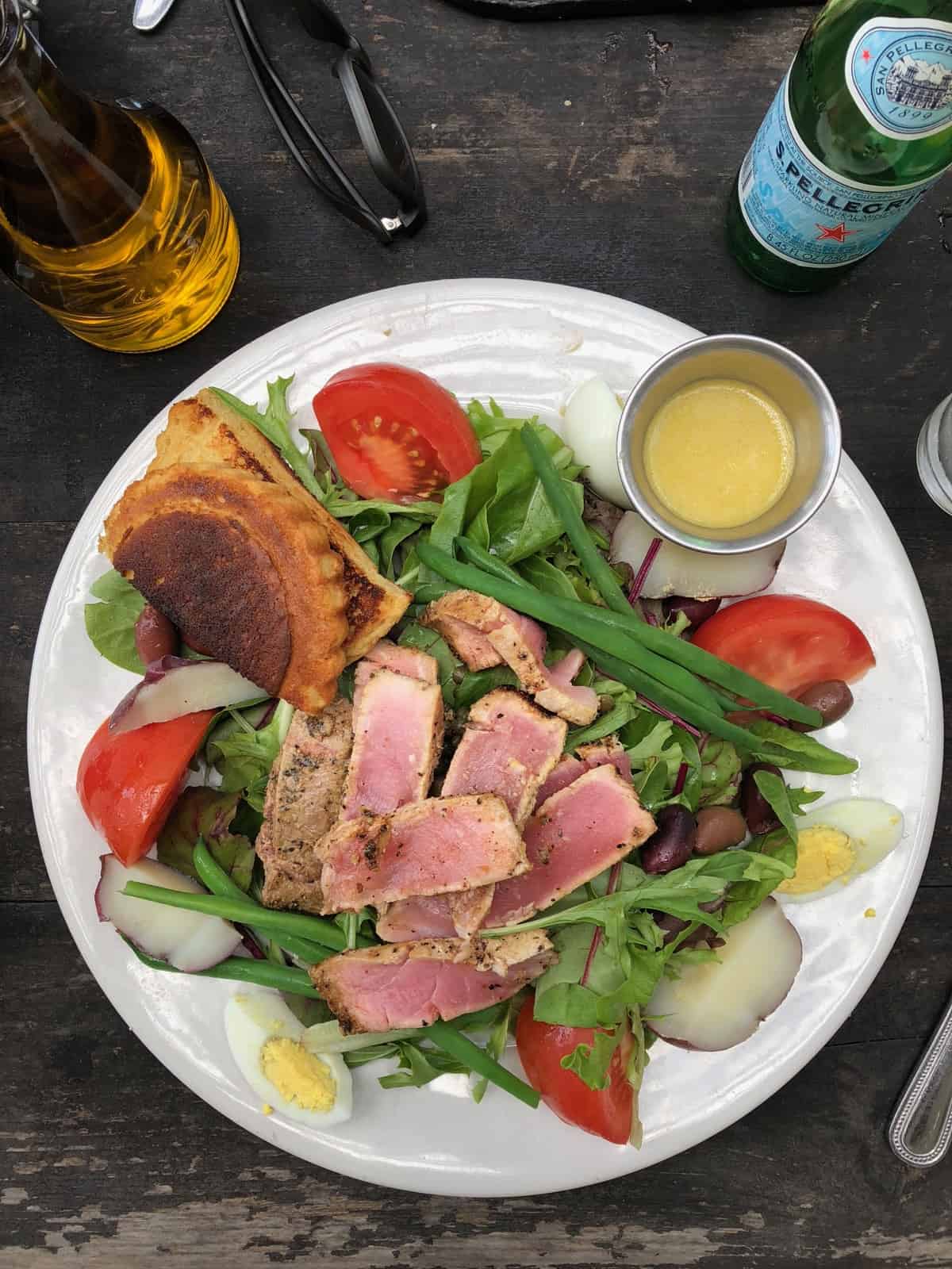Tuna nicoise salad with gluten free bread and dressing on the side