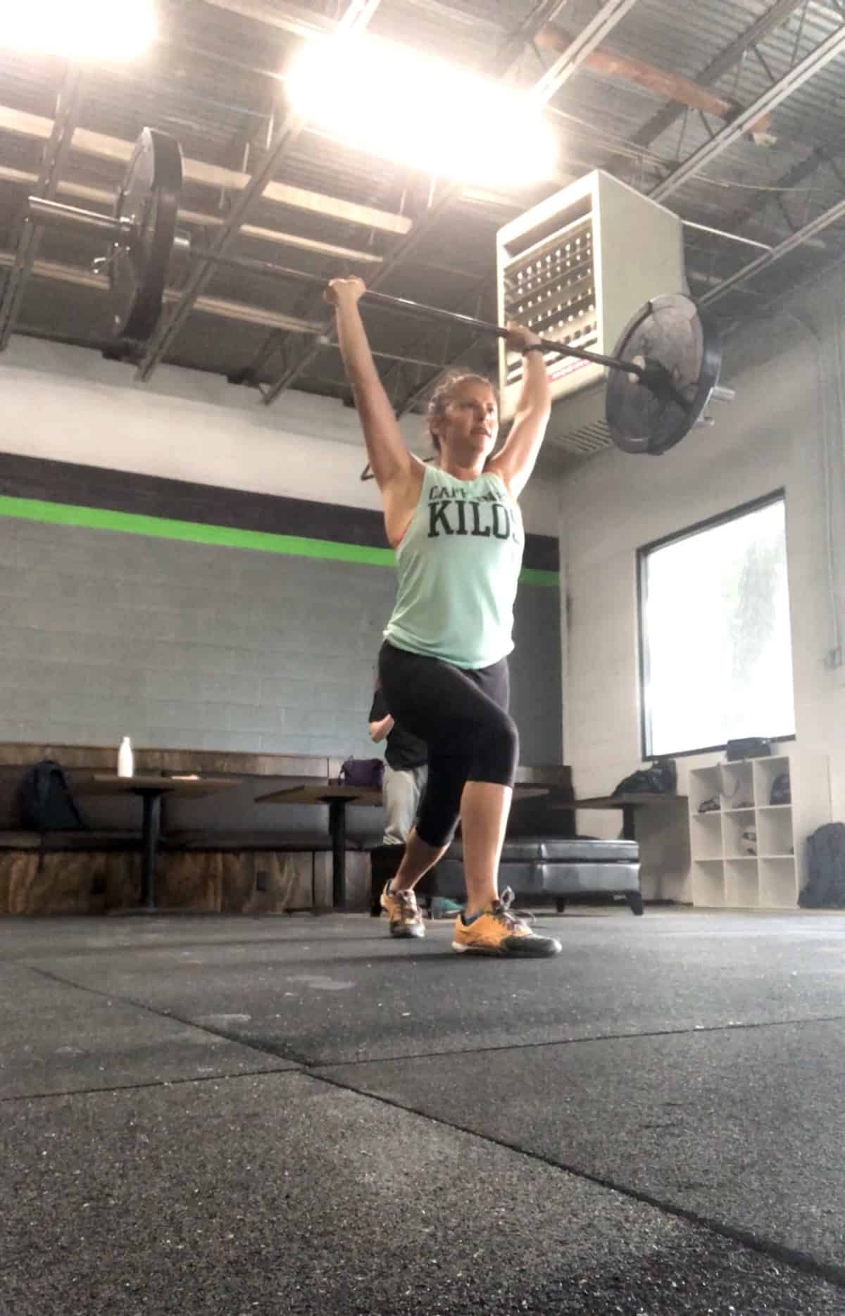 Girl in the catch position of a split jerk with a barbell over her head