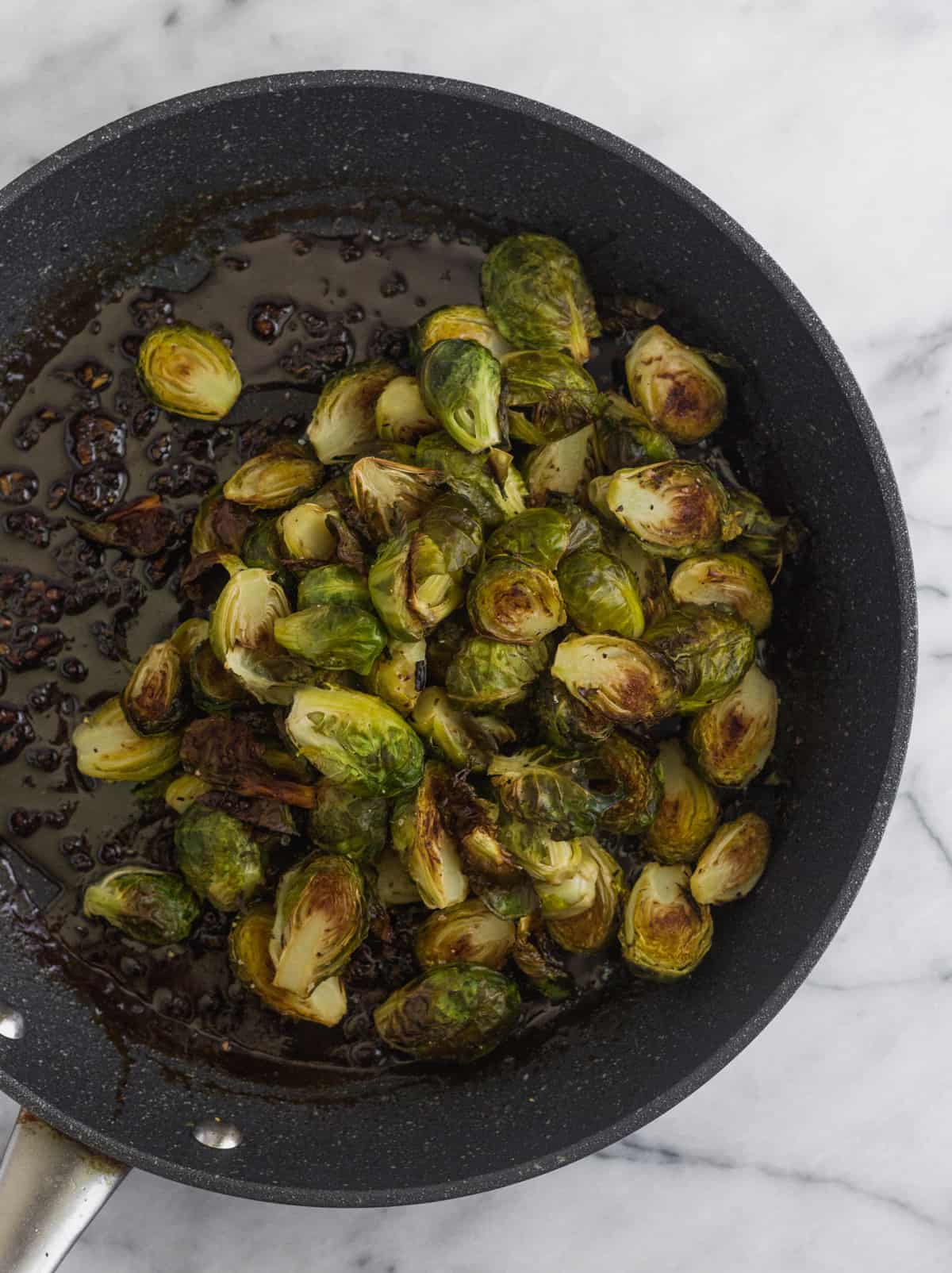Saute pan filled with miso sauce and roasted brussels sprouts