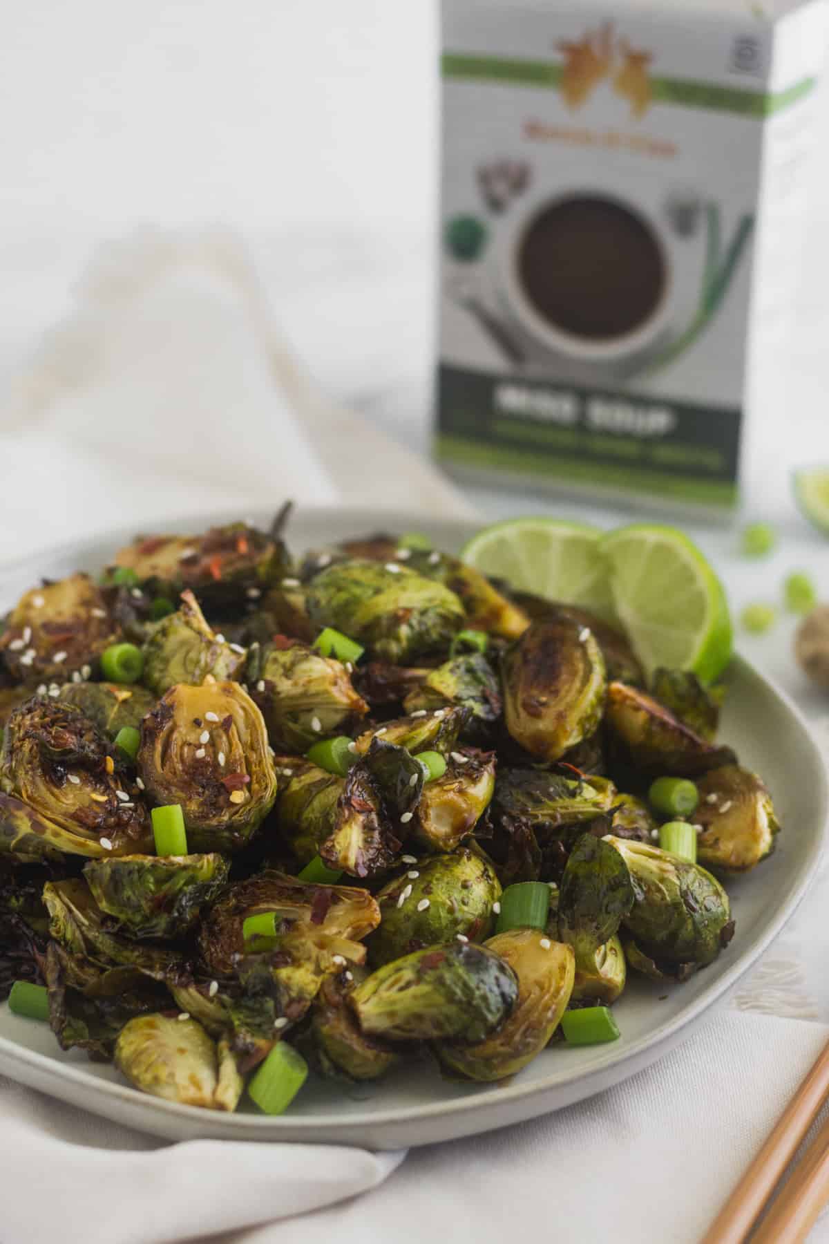 Plate of miso glazed brussels sprouts with a box of miso soup behind them