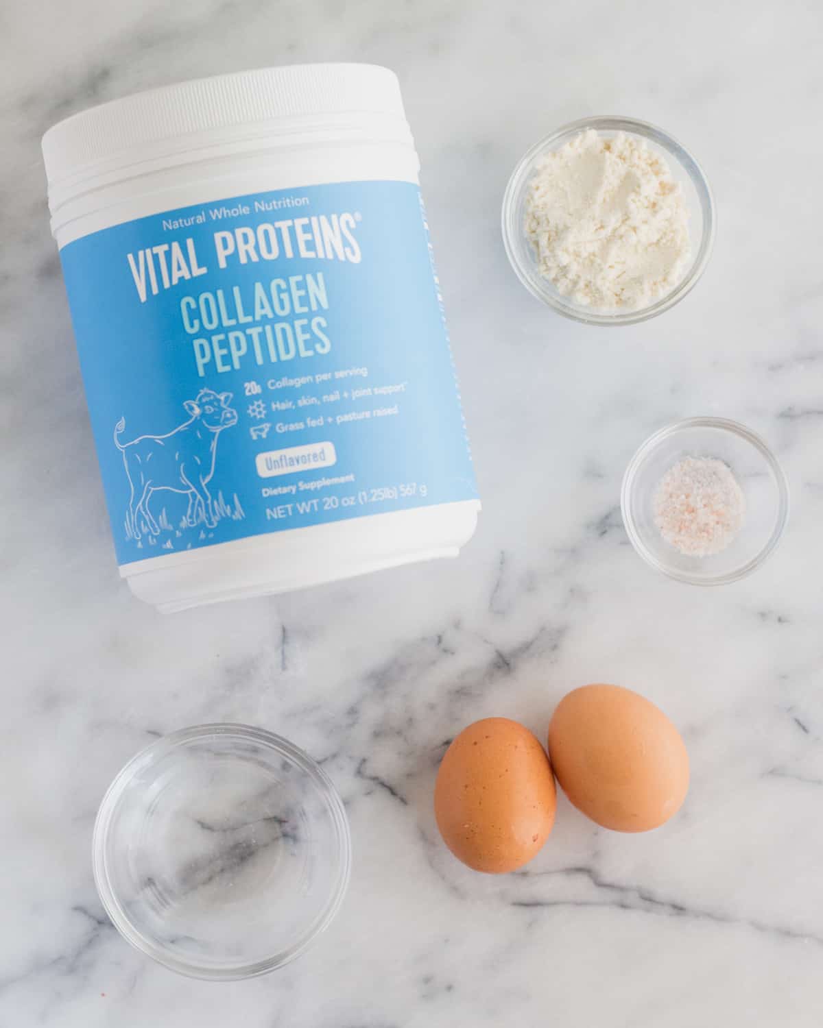Collagen peptides, coconut flour, salt, 2 eggs, and a bowl of water on a counter top