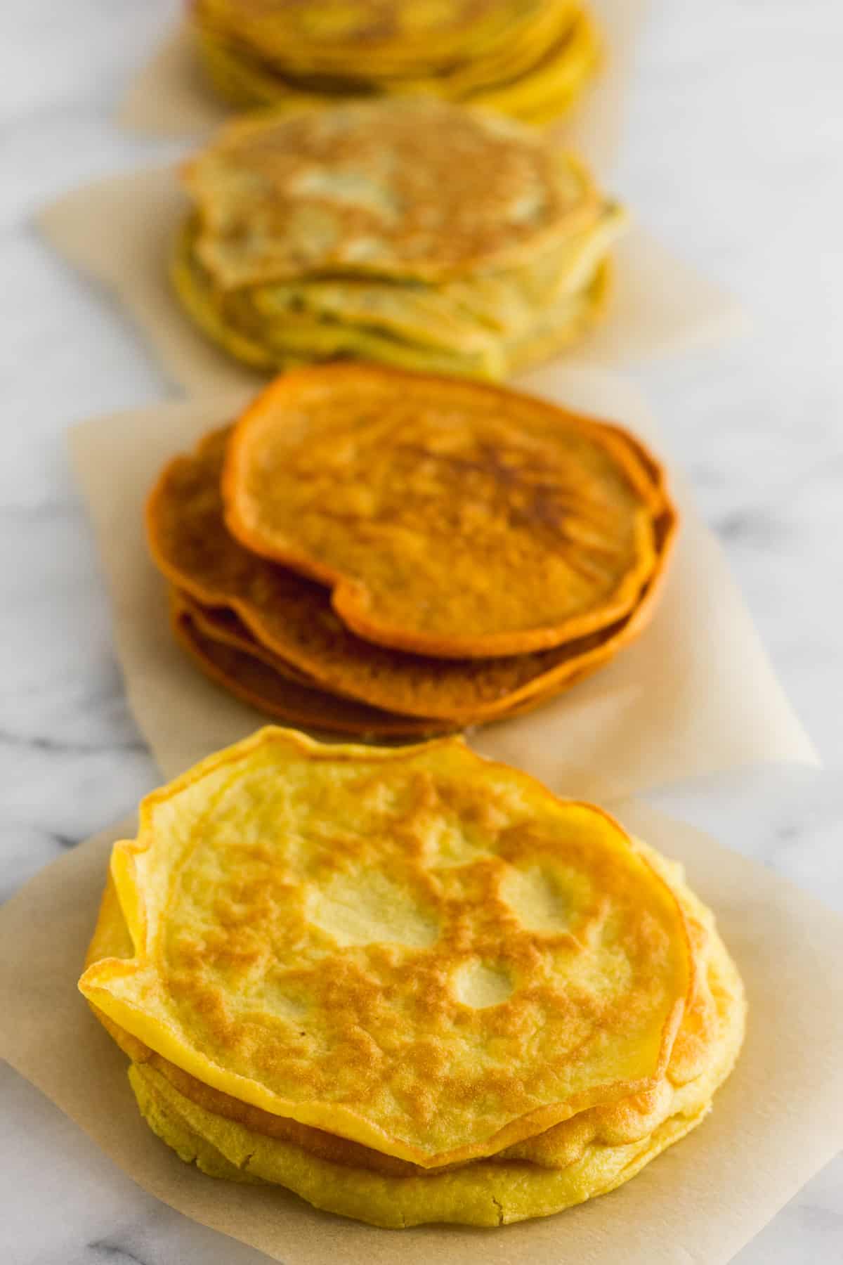 Plain, paprika, garlic & herb, and turmeric paleo tortillas on a white counter top