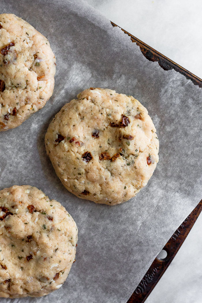 Raw chicken burger patties on a baking sheet lined with parchment paper.