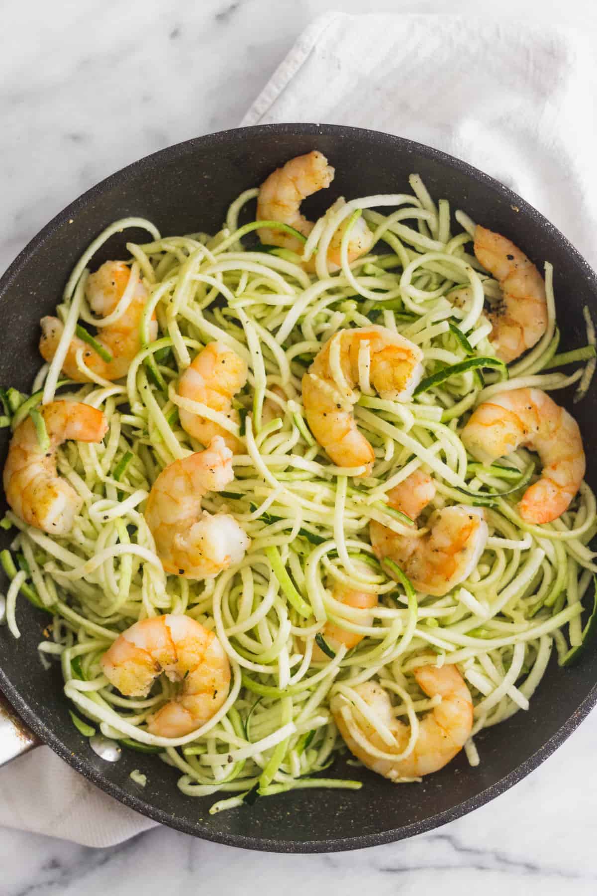 Large sauté pan filled with zucchini noodles and cooked shrimp