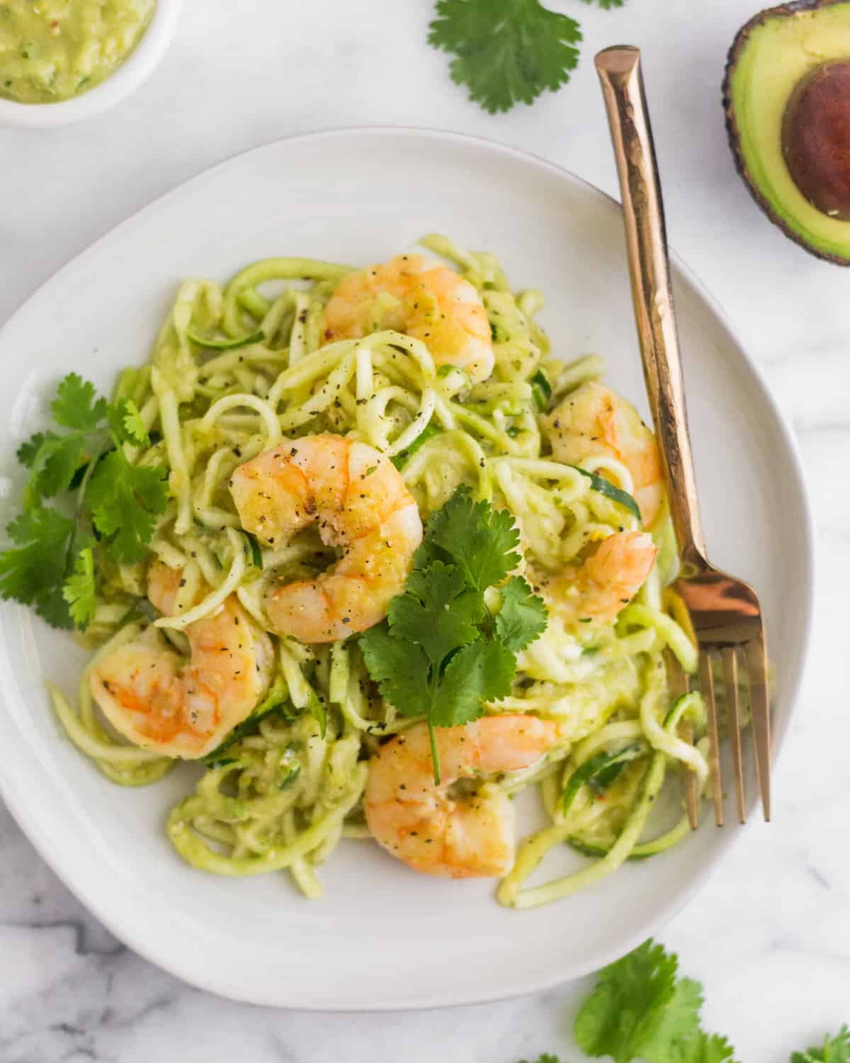 Overhead shot of a white plate with Whole30 Tomatillo Salsa Shrimp Zucchini Noodles on it on a white countertop