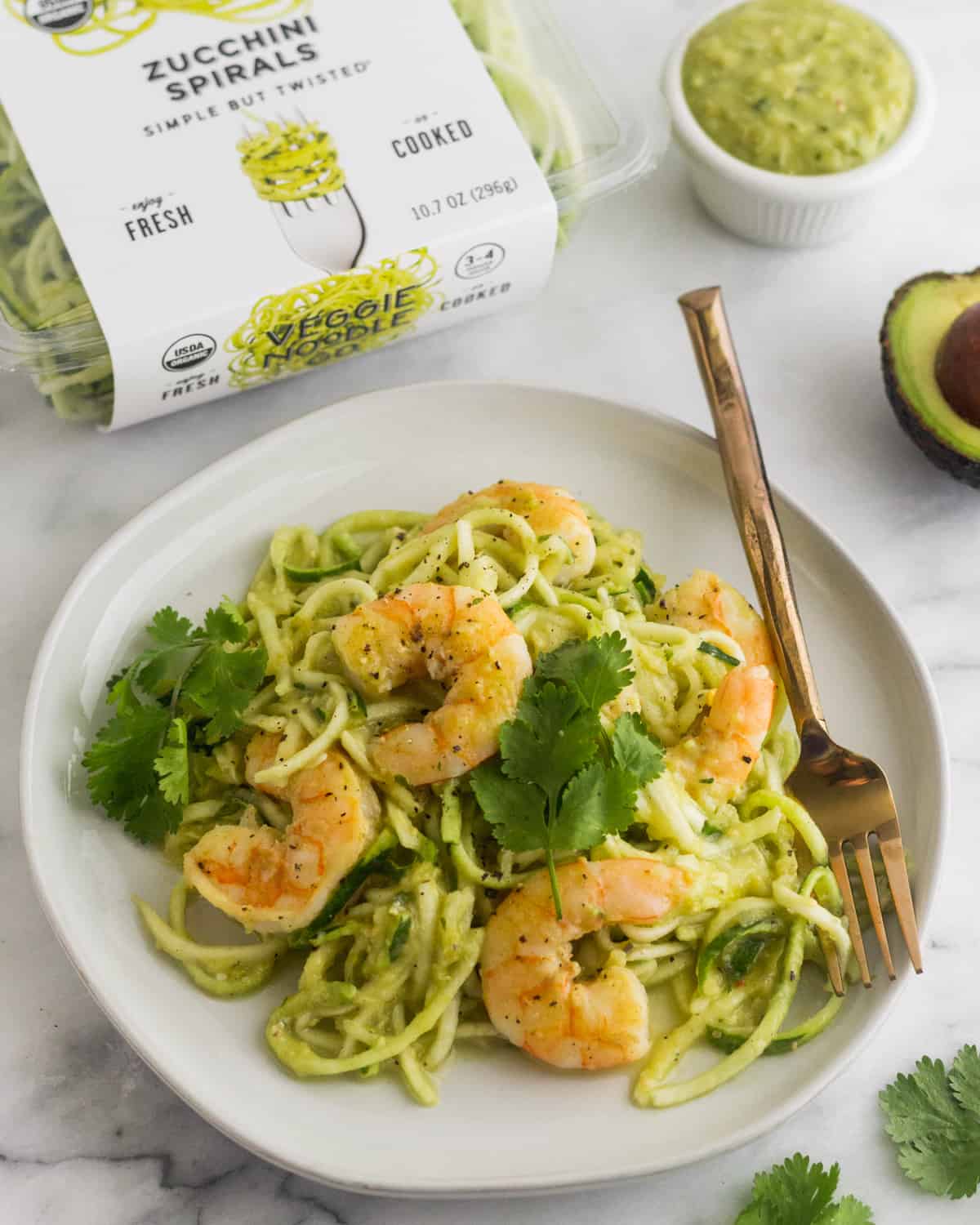 White plate with Whole30 Tomatillo Salsa Shrimp Zucchini Noodles with a box of zucchini noodles and a cup of tomatillo salsa behind it
