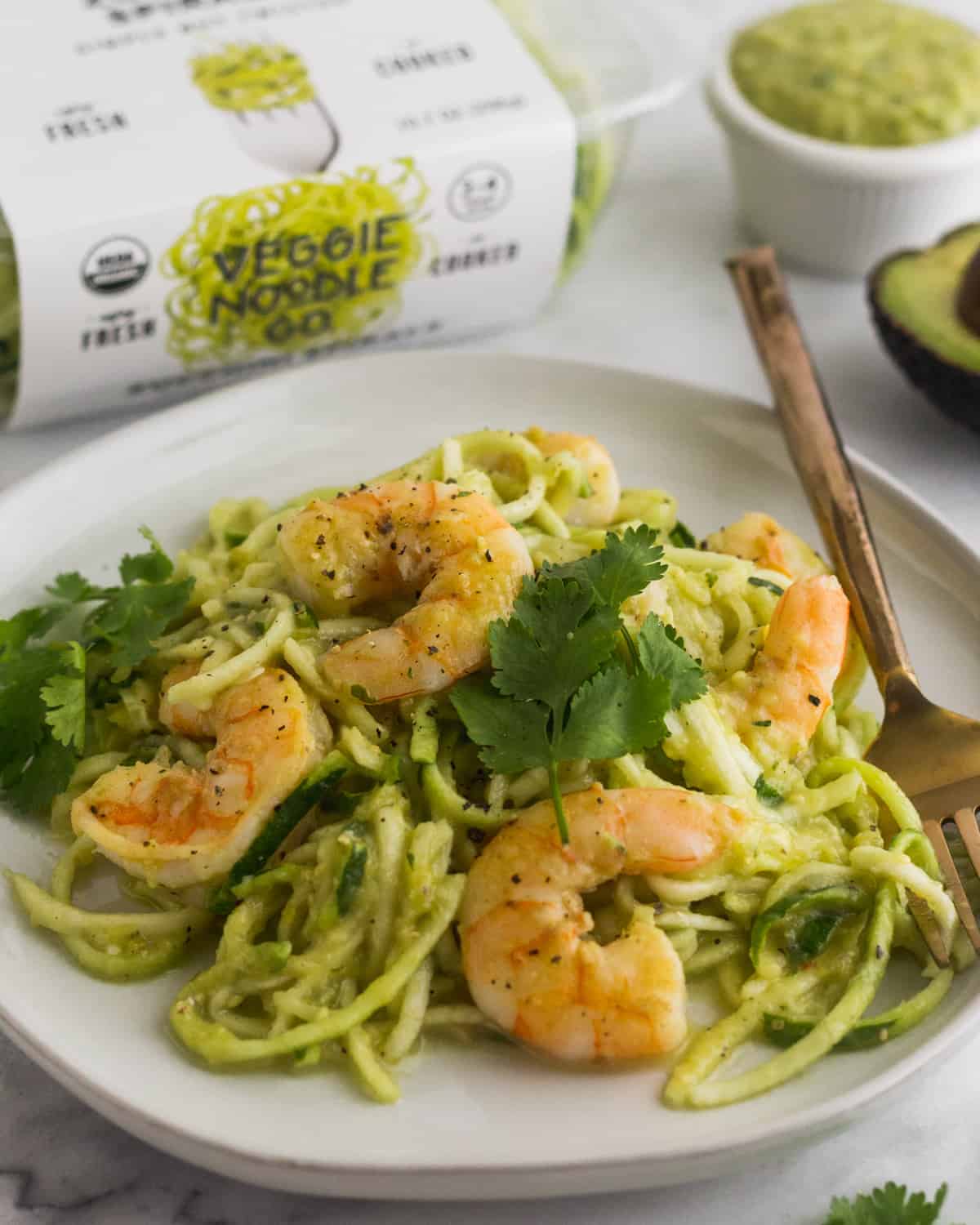 Plate of Whole30 Tomatillo Salsa Shrimp Zucchini Noodles with a fork in them and a box of zucchini noodles behind it