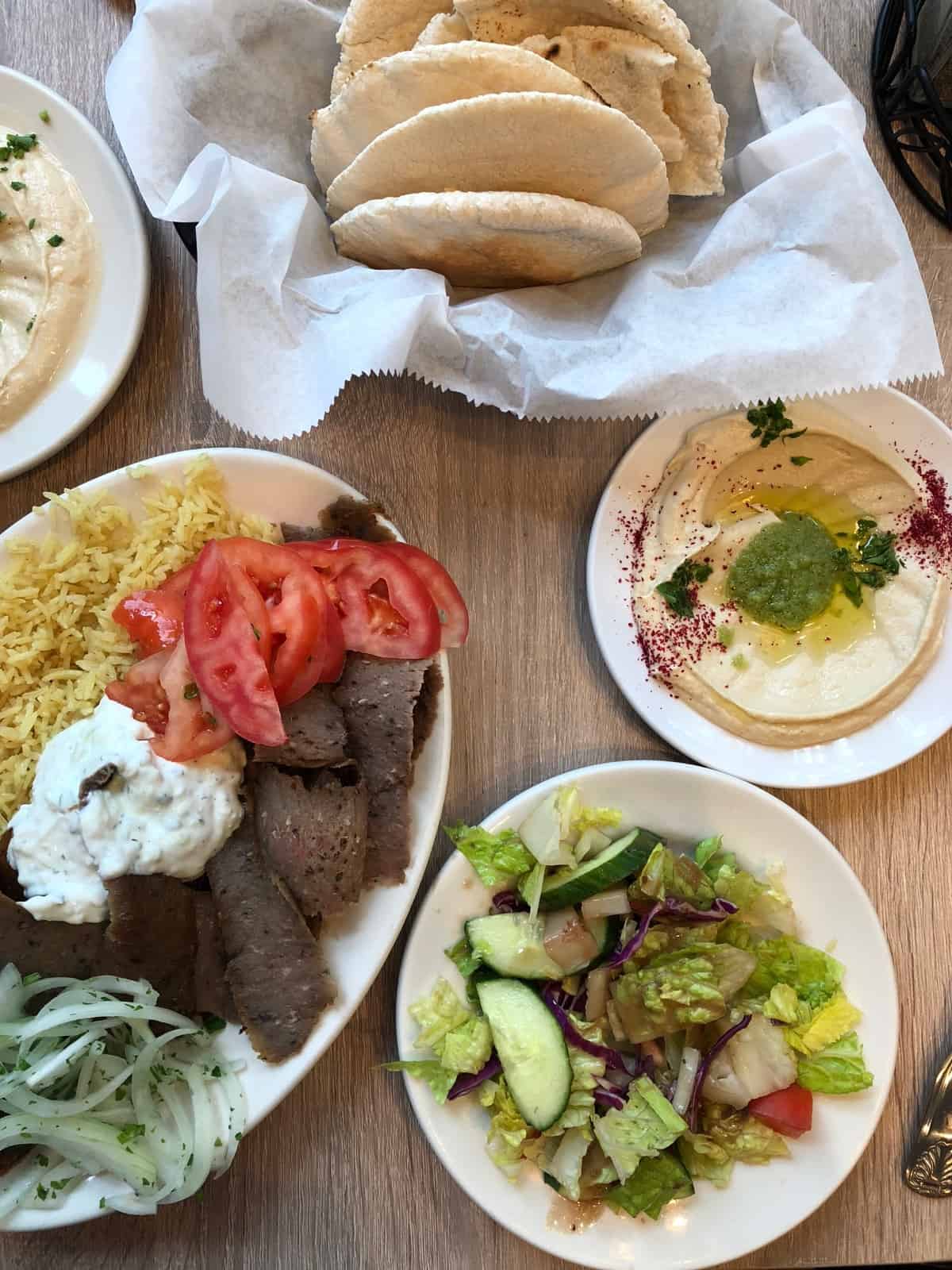 Big basket of pita, a gyro plate, plate of hummus, and a plate of greek salad at Middle Eastern Bakery and Grocery in Chicago, IL