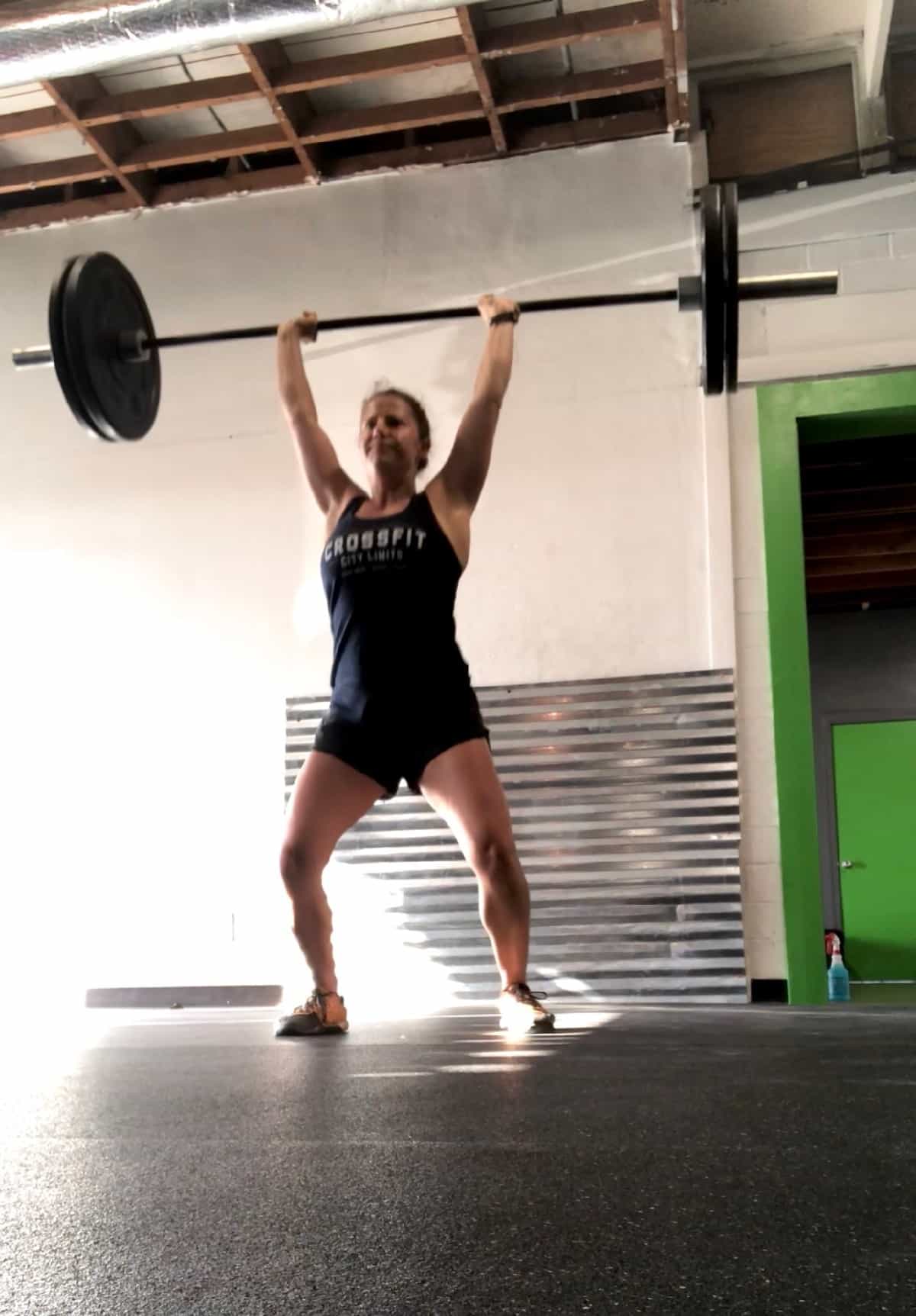 Girl doing a push jerk with the barbell over her head
