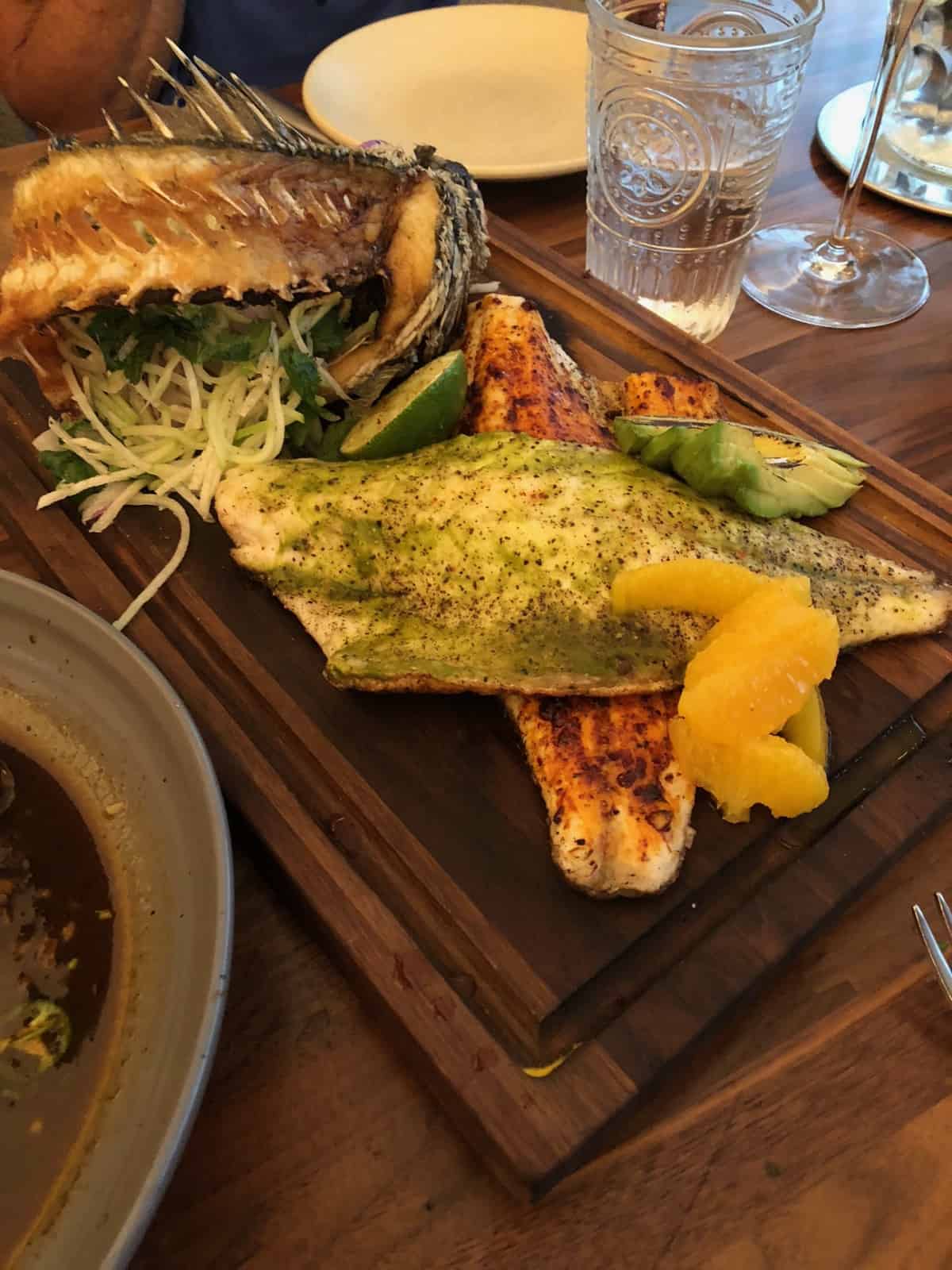 Cutting board with branzino two ways - one with a red sauce and one with a green sauce