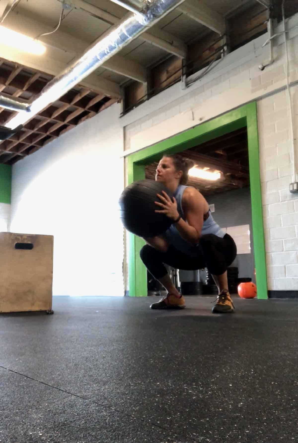 Girl in a gym doing a medball clean