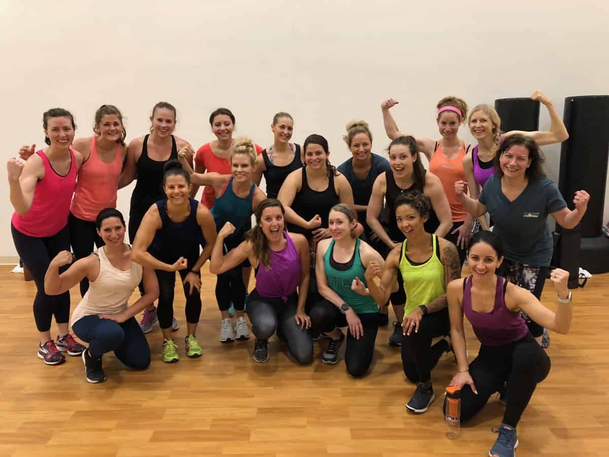 Group of girls post workout in a fitness studio flexing and posing for a picture