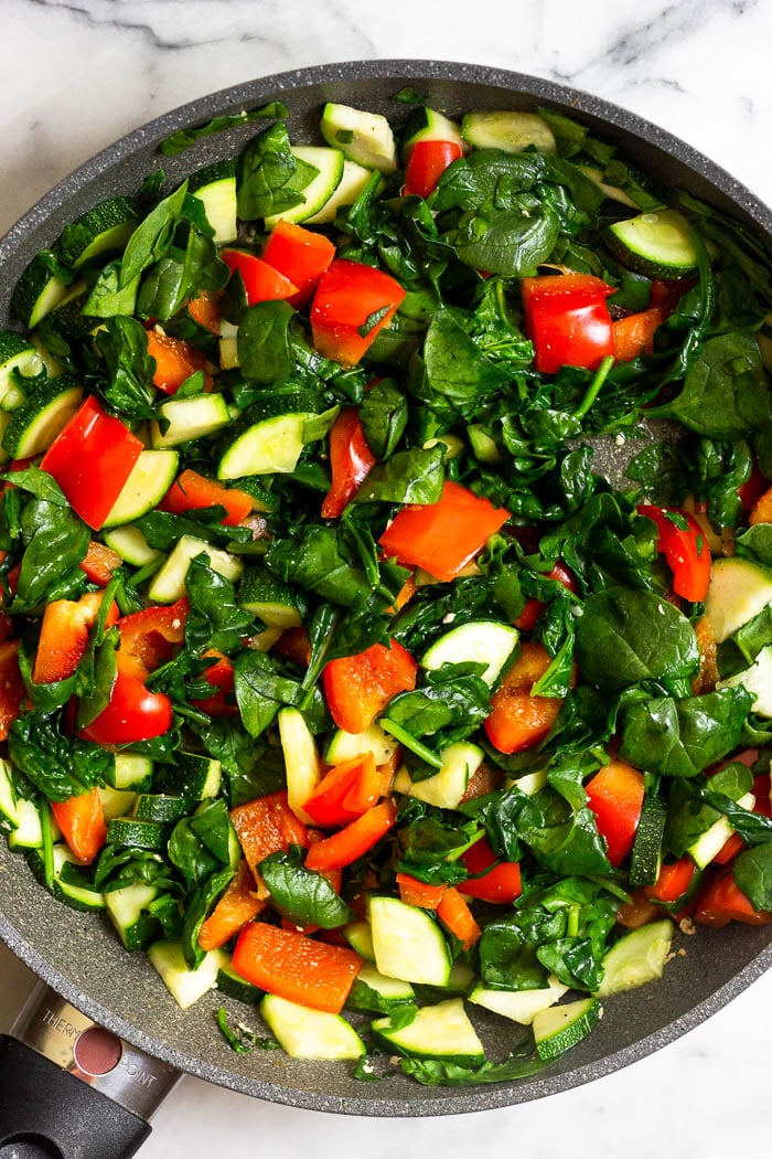 Saute pan with cooked spinach, peppers, and zucchini in it.