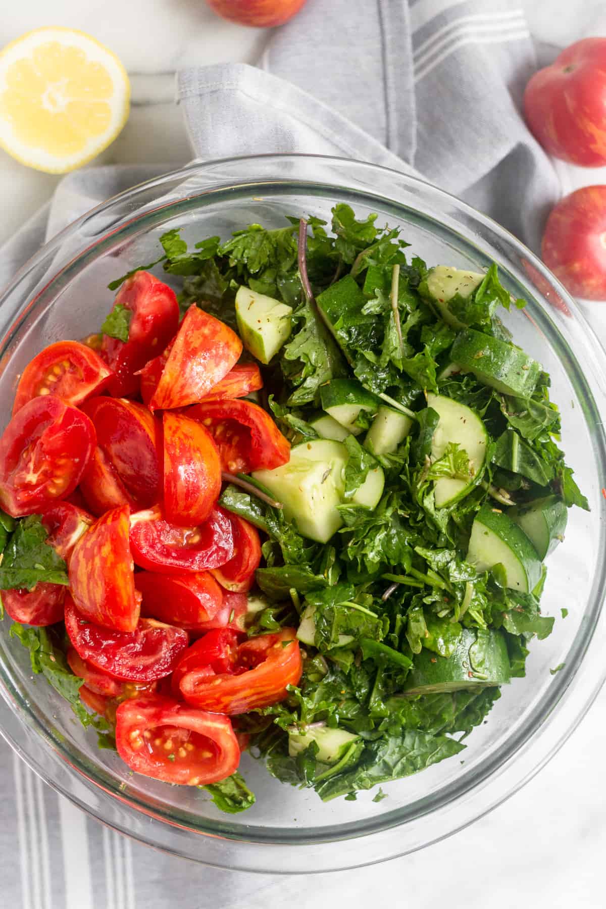 Glass bowl of chopped kale, chopped cucumbers, and quartered tomatoes