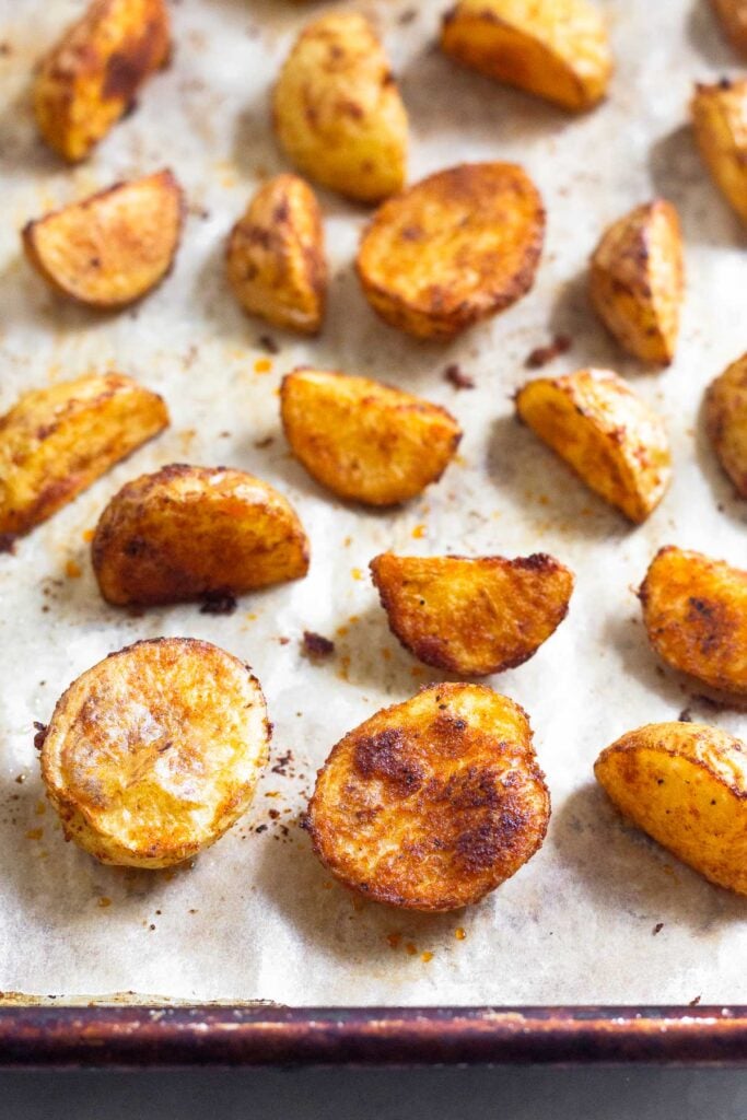 Crispy breakfast potatoes spread out on a baking sheet.