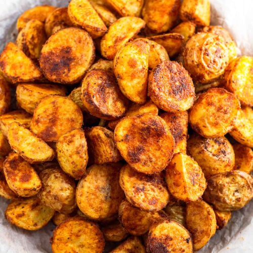 Crispy breakfast potatoes on a wooden plate lined with parchment paper.