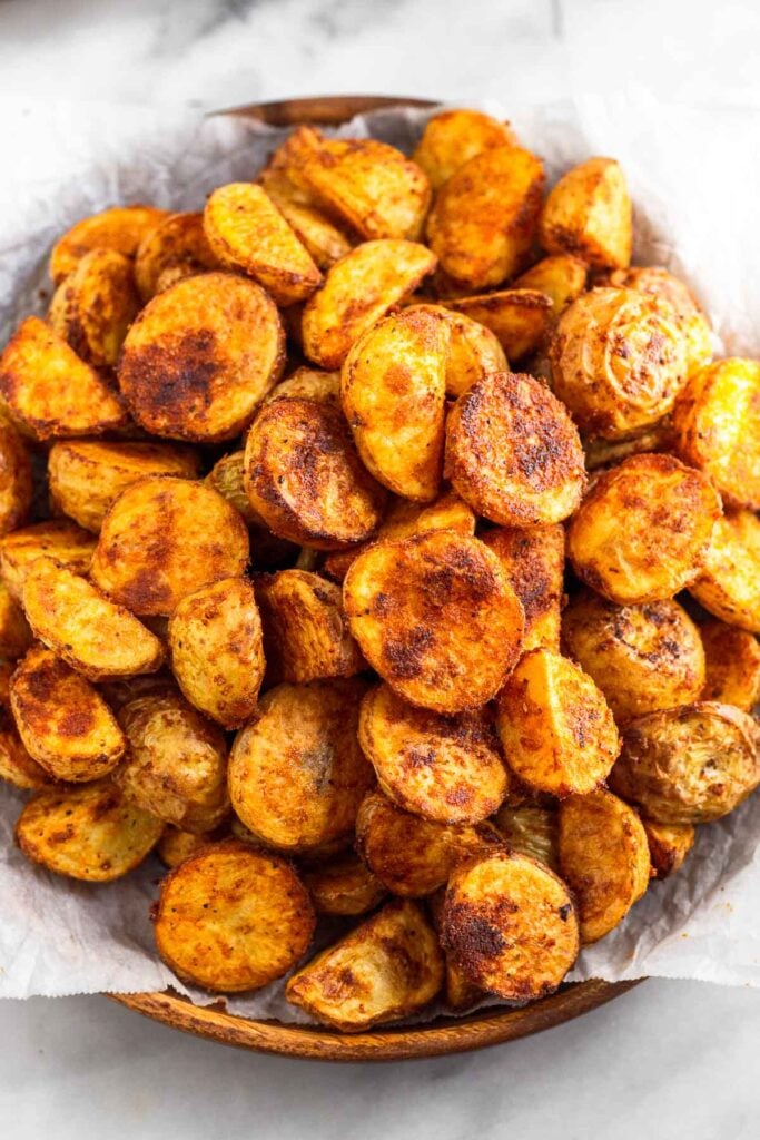 Crispy breakfast potatoes on a wooden plate lined with parchment paper.