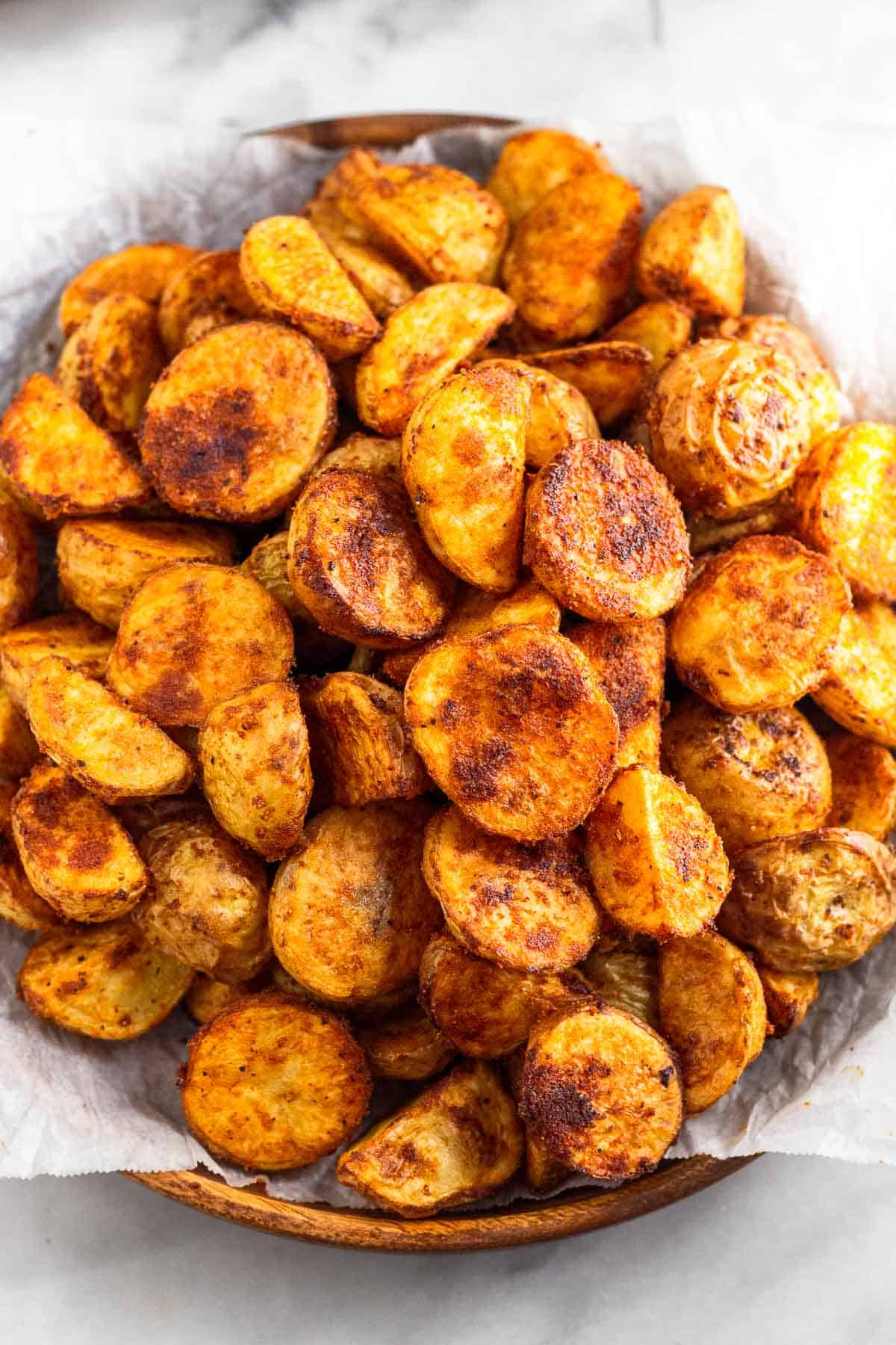 Crispy breakfast potatoes on a wooden plate lined with parchment paper.