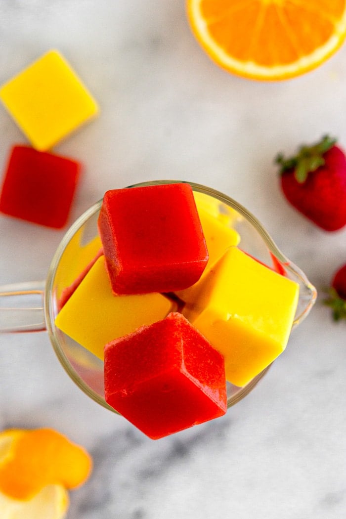 Overhead shot of paleo gummies in a glass jar. Around it is more gummies and some fresh strawberries and oranges.
