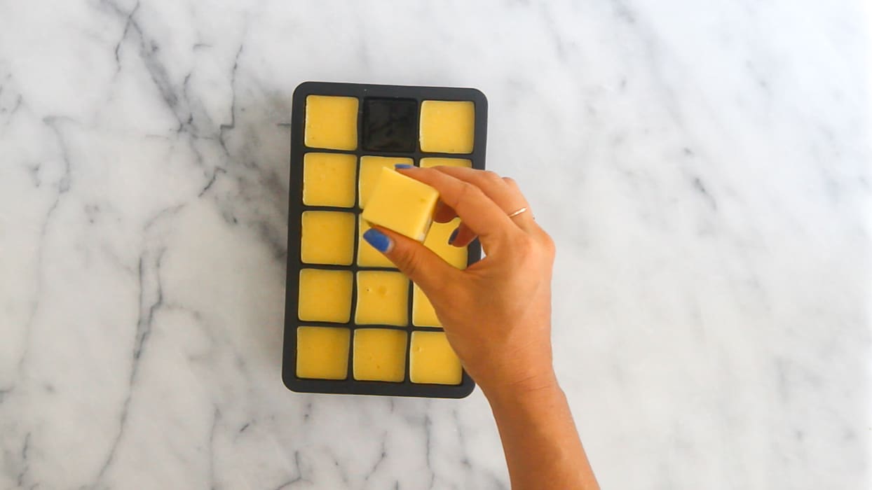 Overhead shot of gelatin gummies in a silicone mold with one taken our and being held above the rest.