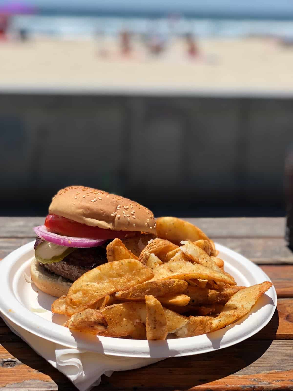 Burger and fries from Woody's on the strand with the beach in the background in San Diego