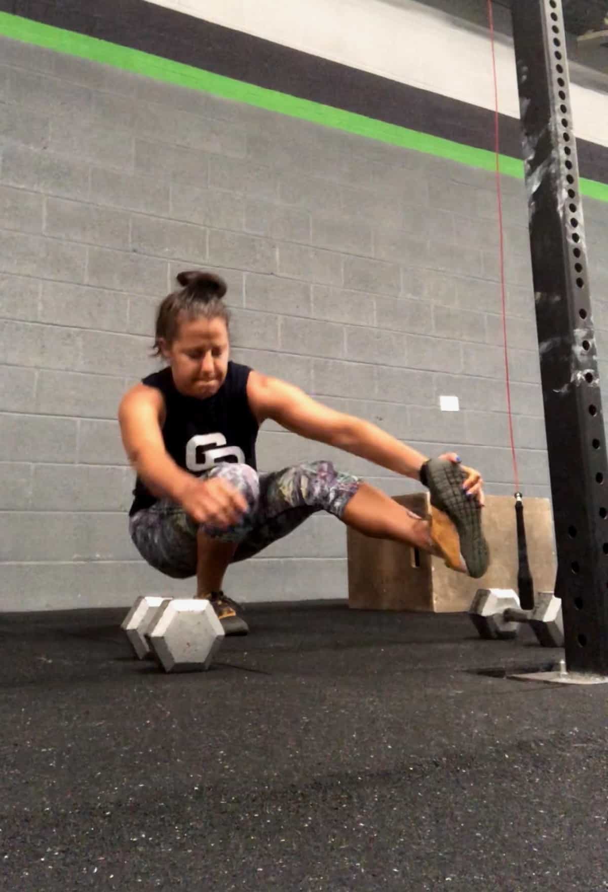 Girl in a CrossFit gym doing a pistol or one legged squat