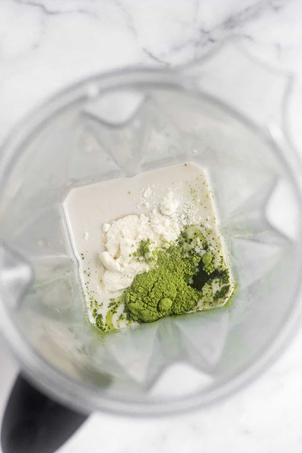 Blender filled with almond milk, collagen, matcha, maple syrup, and coconut creamer