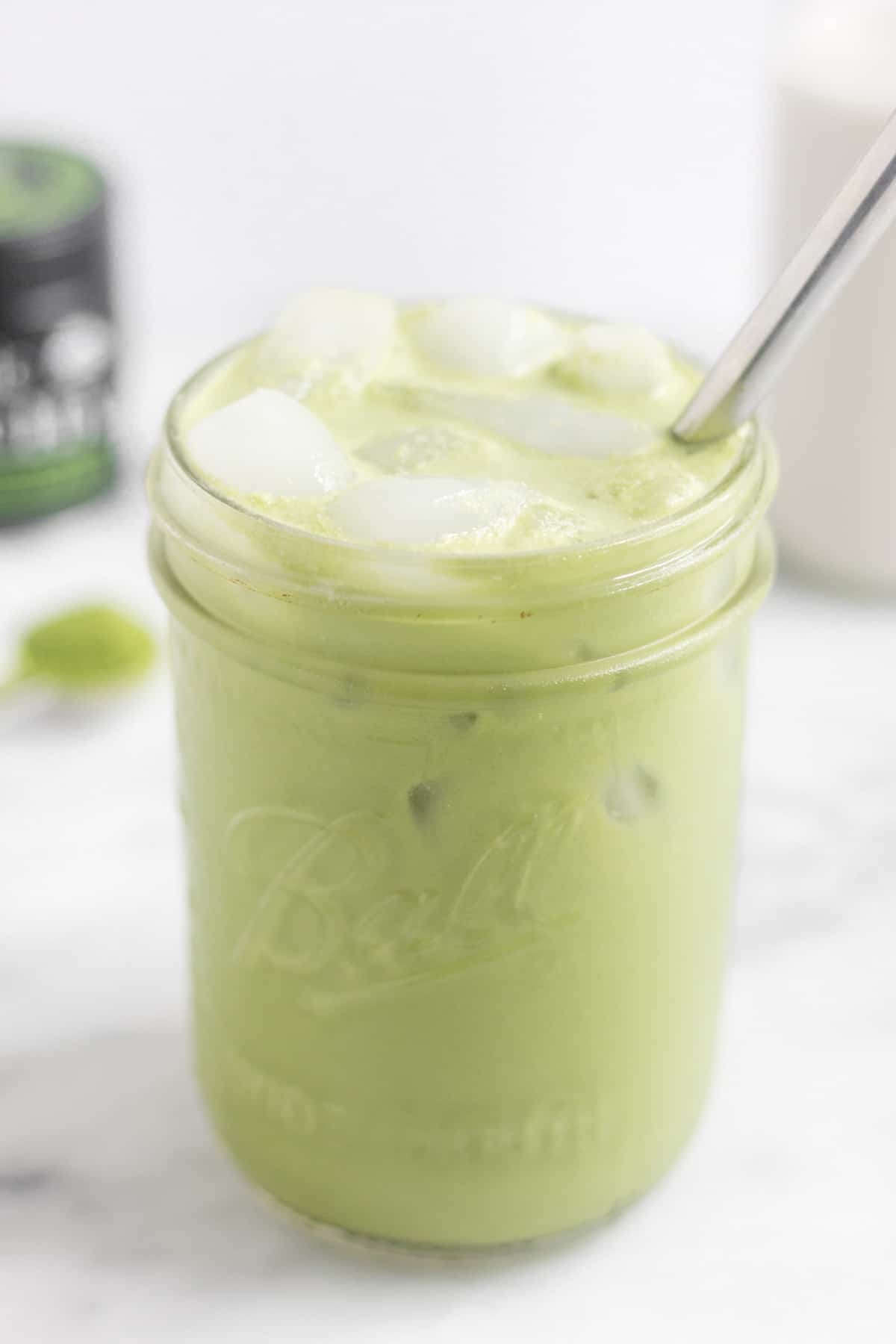 Large glass filled with a paleo iced matcha latte with a metal straw in it
