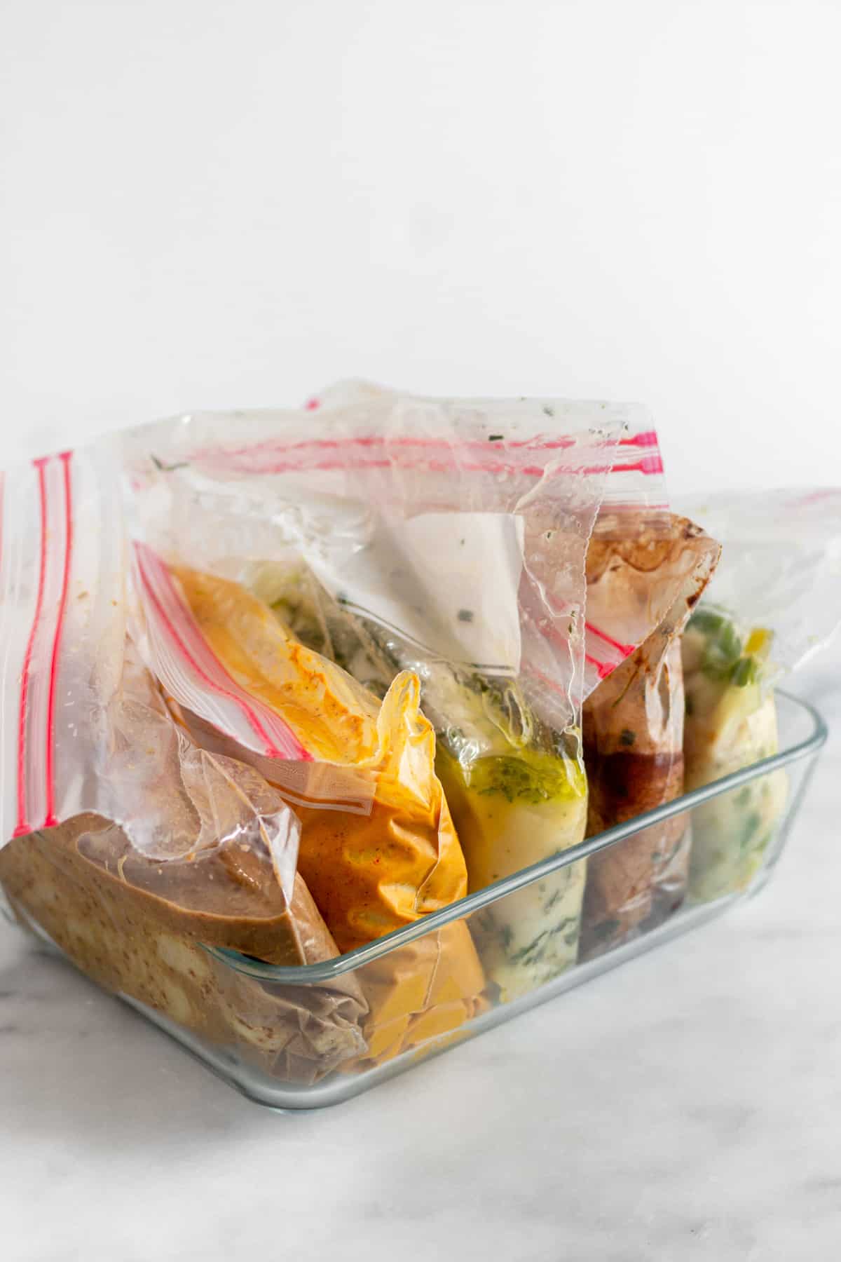 Glass baking dish with 5 bags of whole30 chicken marinade and chicken in each one