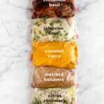 5 plastic bags on white counter top filled with Whole30 Chicken Marinade 5 different ways. Text overlay of what each marinade is - cinnamon basil, jalapeño lime, coconut curry, mustard balsamic, citrus rosemary.