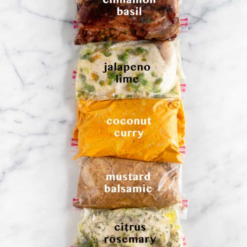 5 plastic bags on white counter top filled with Whole30 Chicken Marinade 5 different ways. Text overlay of what each marinade is - cinnamon basil, jalapeño lime, coconut curry, mustard balsamic, citrus rosemary.