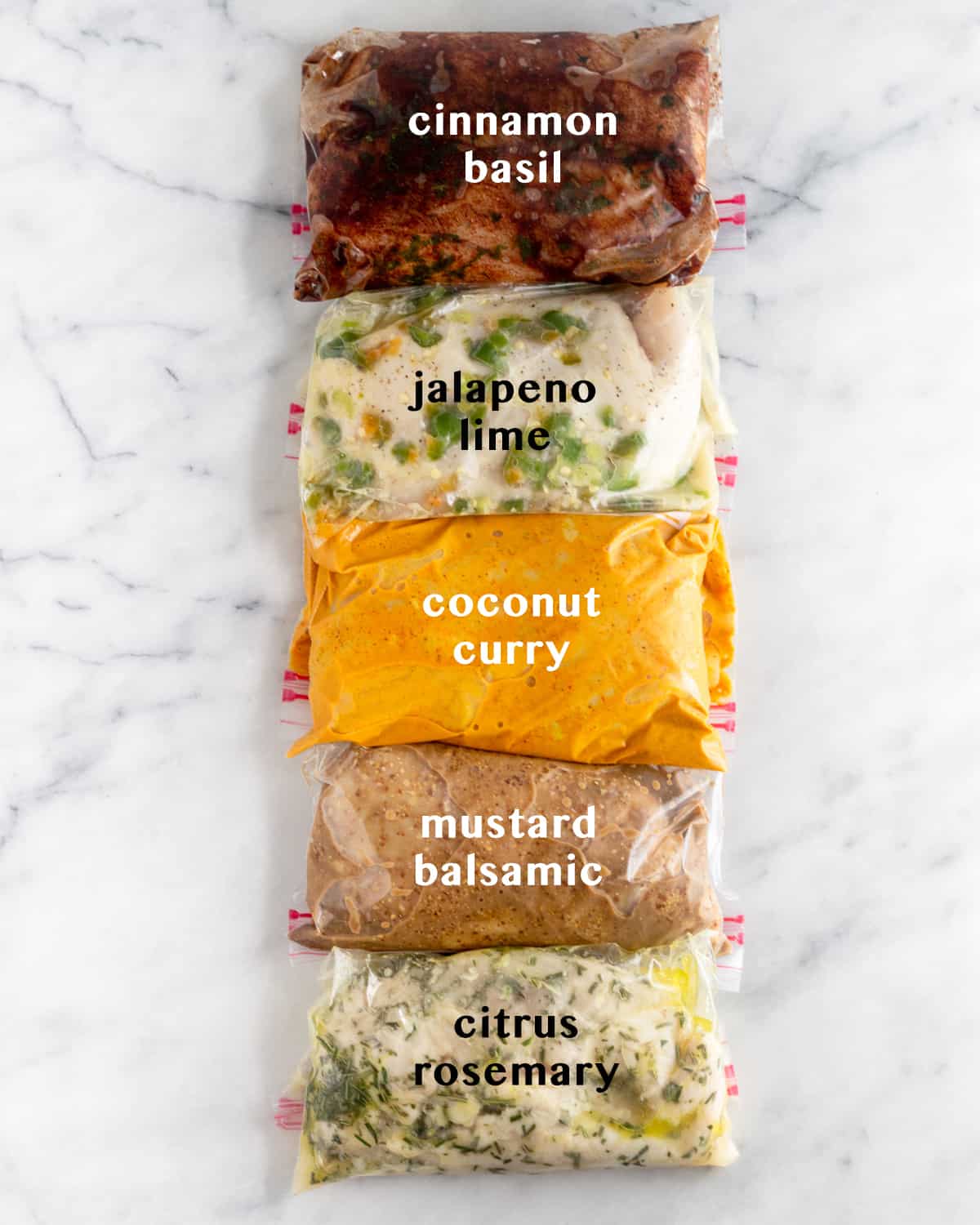 5 plastic bags on white counter top filled with Whole30 Chicken Marinade 5 different ways. Text overlay of what each marinade is - cinnamon basil, jalapeño lime, coconut curry, mustard balsamic, citrus rosemary.