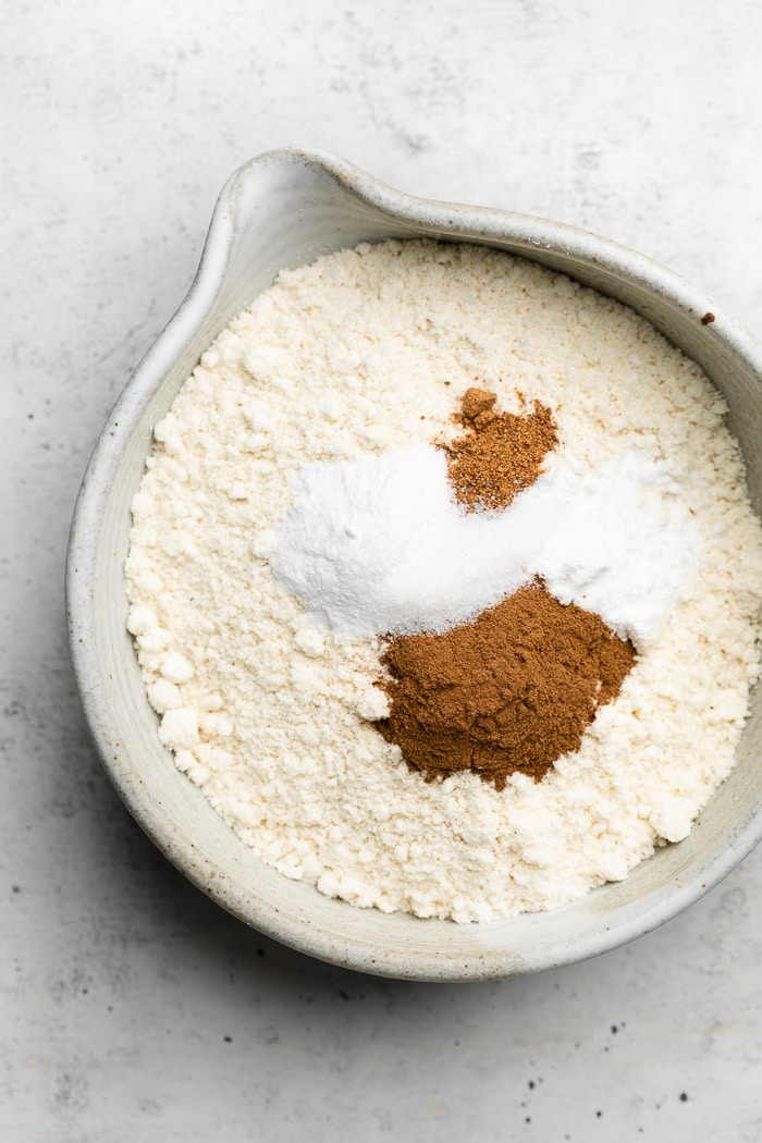 Large bowls of flour with baking soda, baking powder, and spices sprinkled on top.