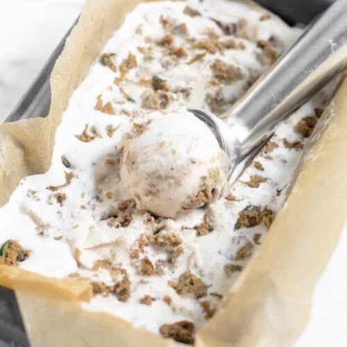 Dairy Free Paleo Zucchini Bread Ice Cream in a small bread pan with an ice cream scoop and a scoop of ice cream in it