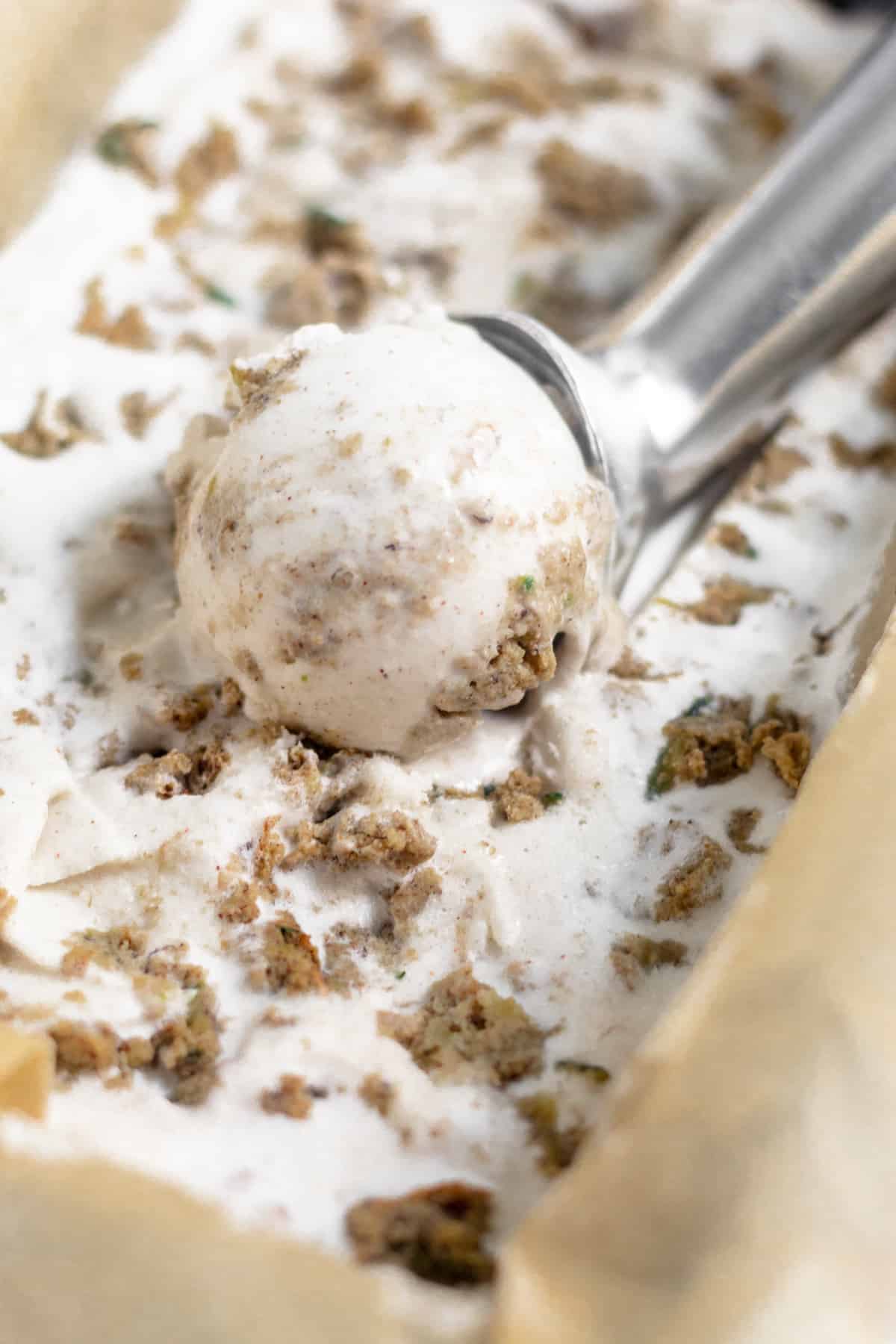 Ice cream scoop filled with ice cream in a loaf pan of Dairy Free Paleo Zucchini Bread Ice Cream