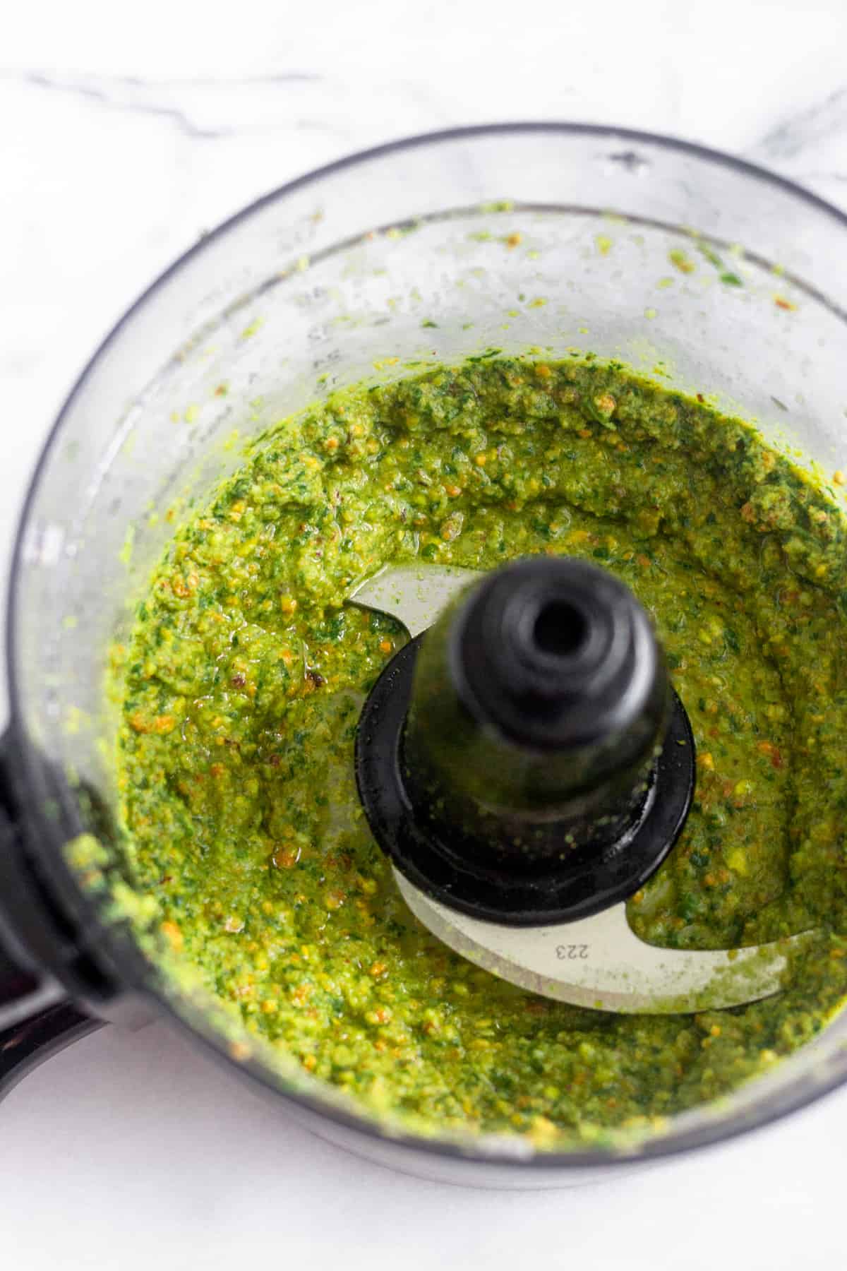 Food processor filled with homemade pistachio pesto in it