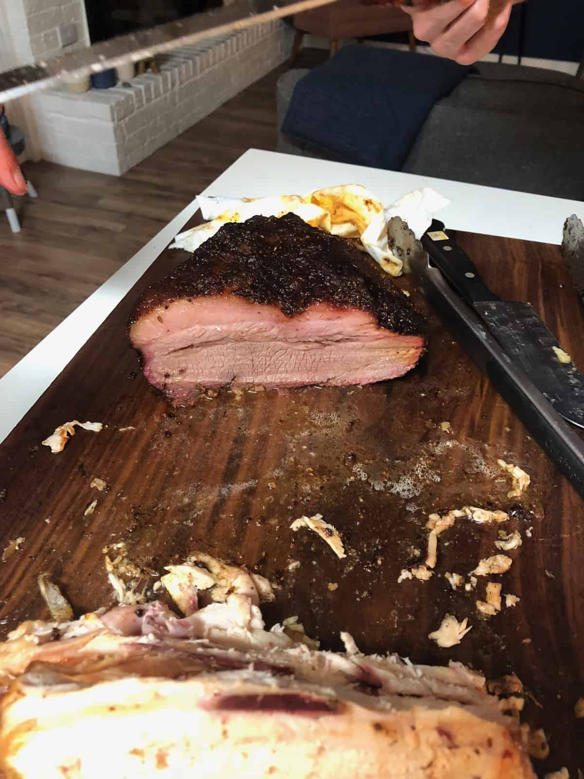 A big piece of brisket being cut on a wooden cutting board