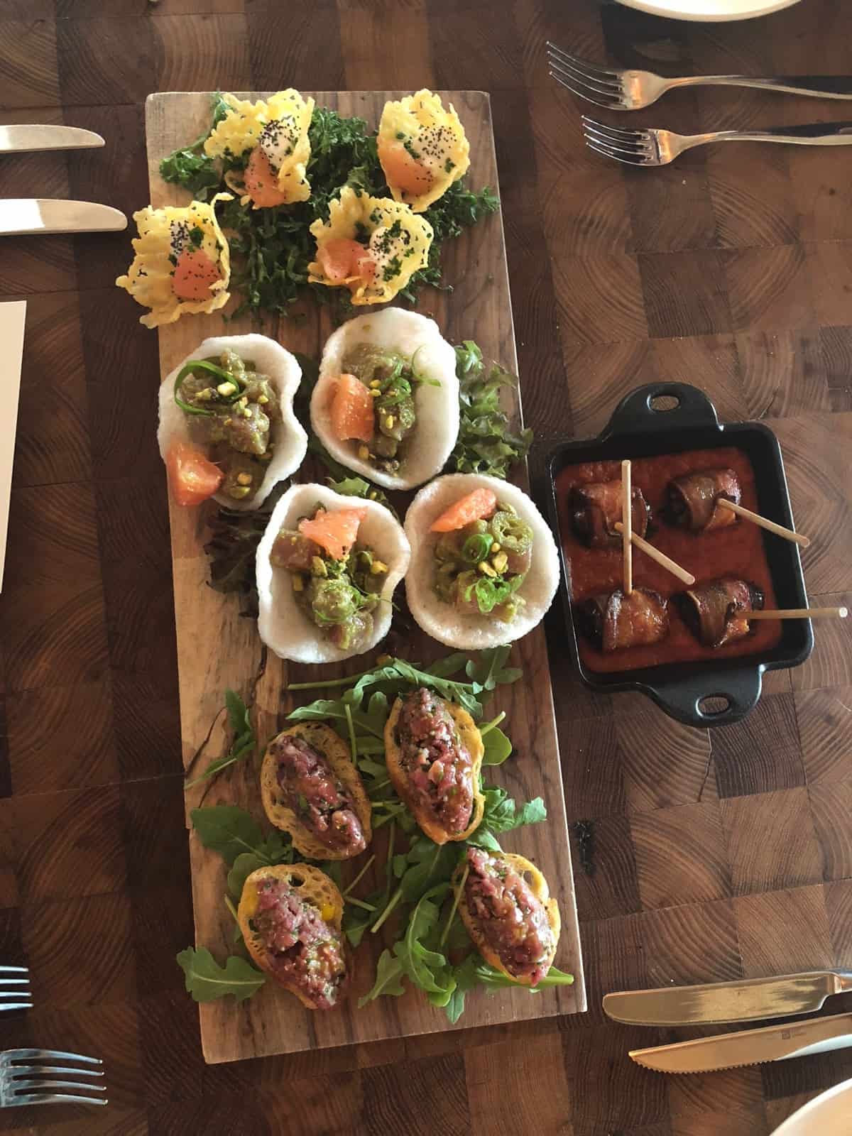 4 different appetizers on a cutting board at a wedding tasting